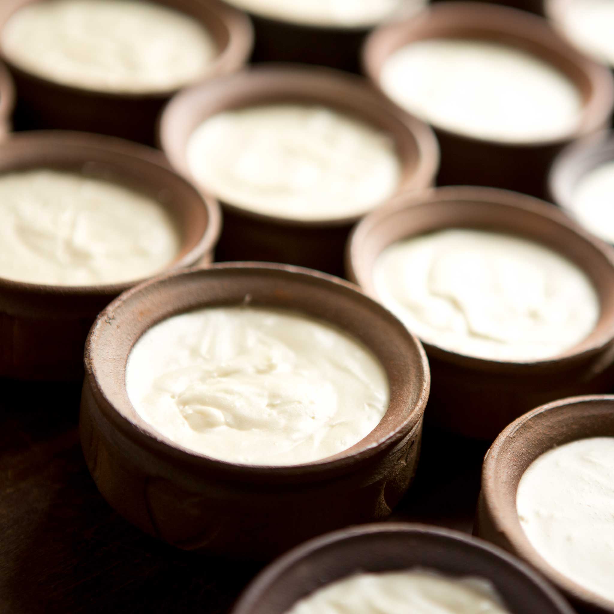 Close-up of natural shea butter cream in a glass jar with a wooden spatula