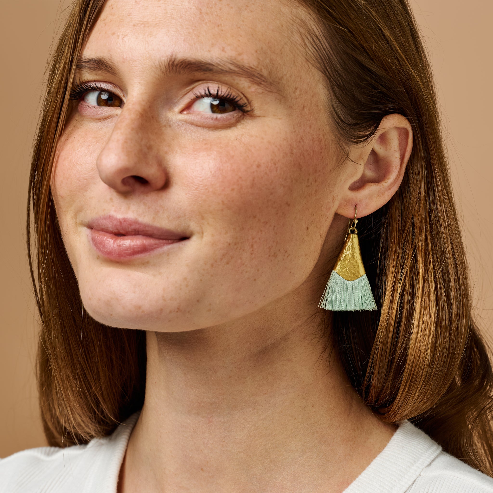 Close-up of sage tassel brass earrings showing intricate craftsmanship