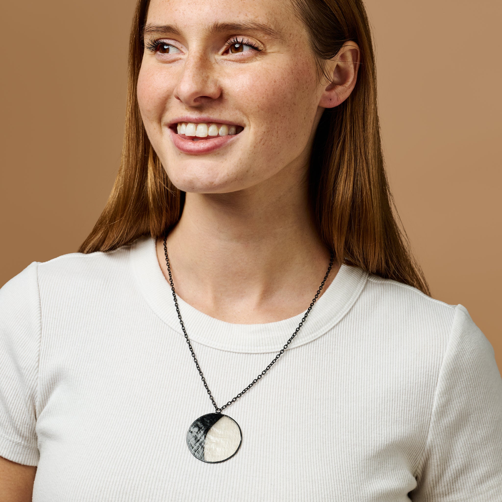 Close-up of waxing moon necklace featuring hand-cut capiz shell framed in brass—perfect celestial necklace.