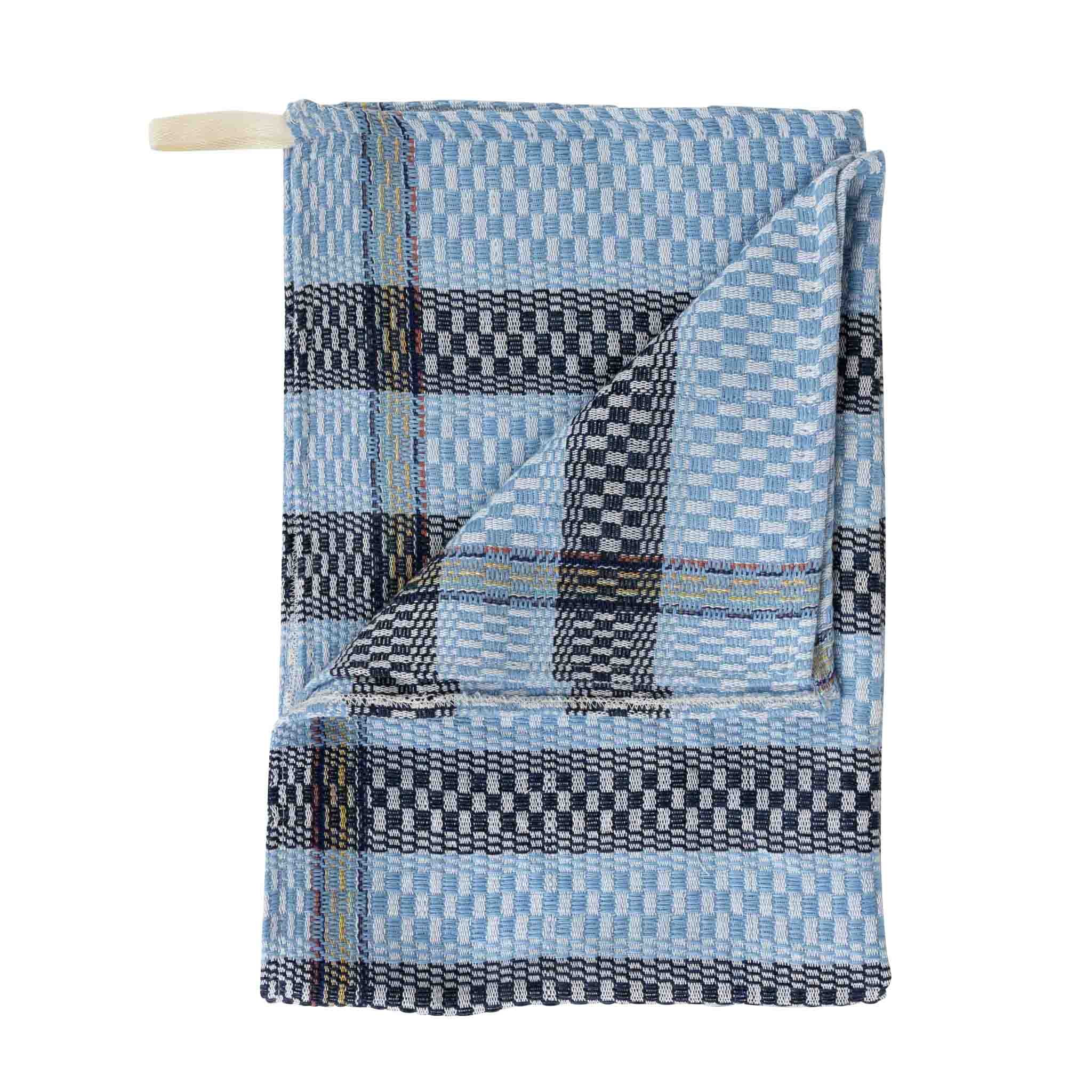 Handwoven blue striped kitchen towel hanging in the kitchen, perfect for drying dishes.
