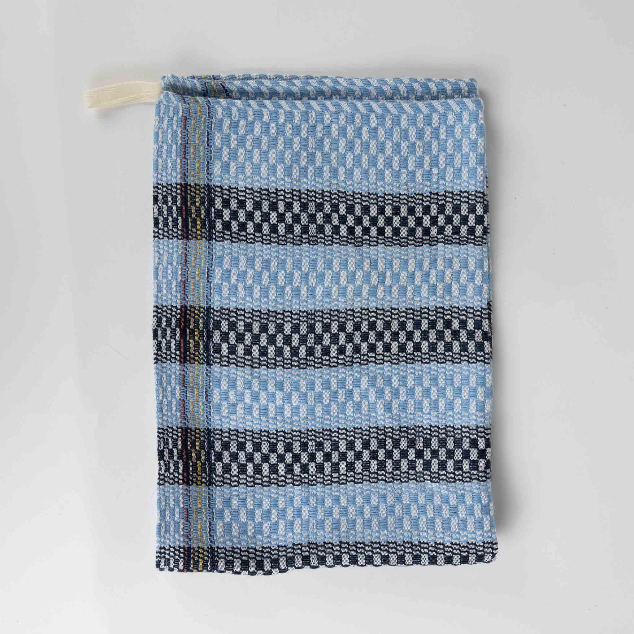 Handwoven blue striped kitchen towel hanging in the kitchen, perfect for drying dishes.