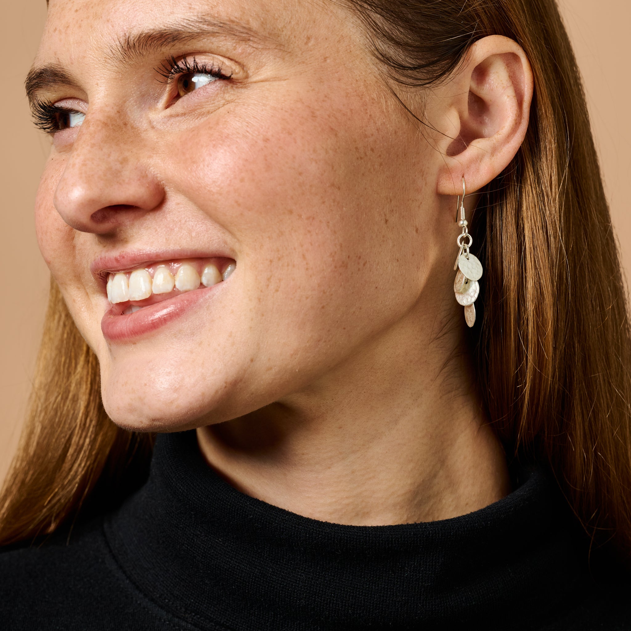 Close-up of silver disk earrings showing hammered texture and cluster arrangement