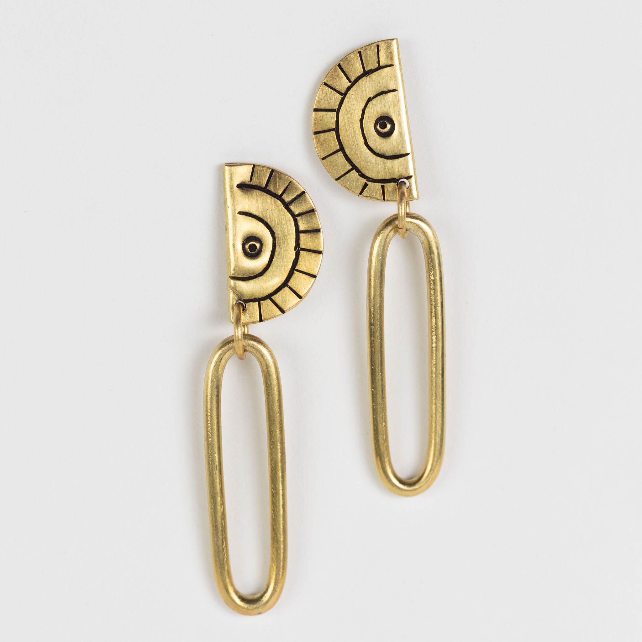 Close-up of handcrafted brass earrings with intricate etching, showcasing the Miduara circle design.