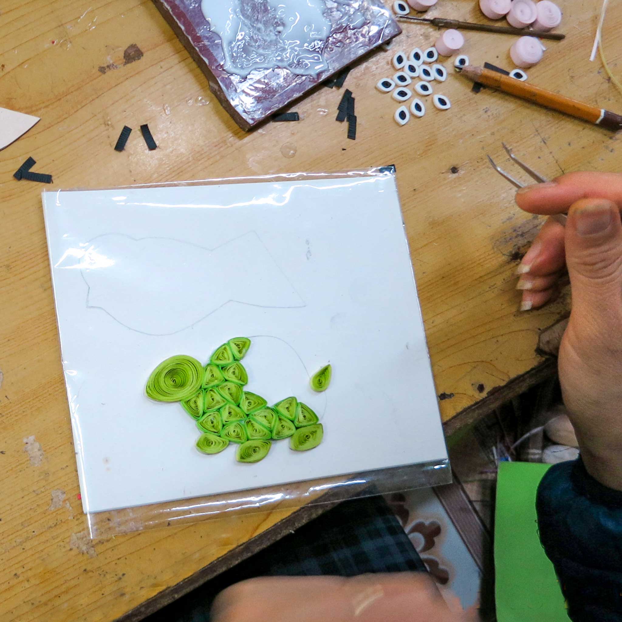 Person holding handmade eco greeting card with floral quilled patterns