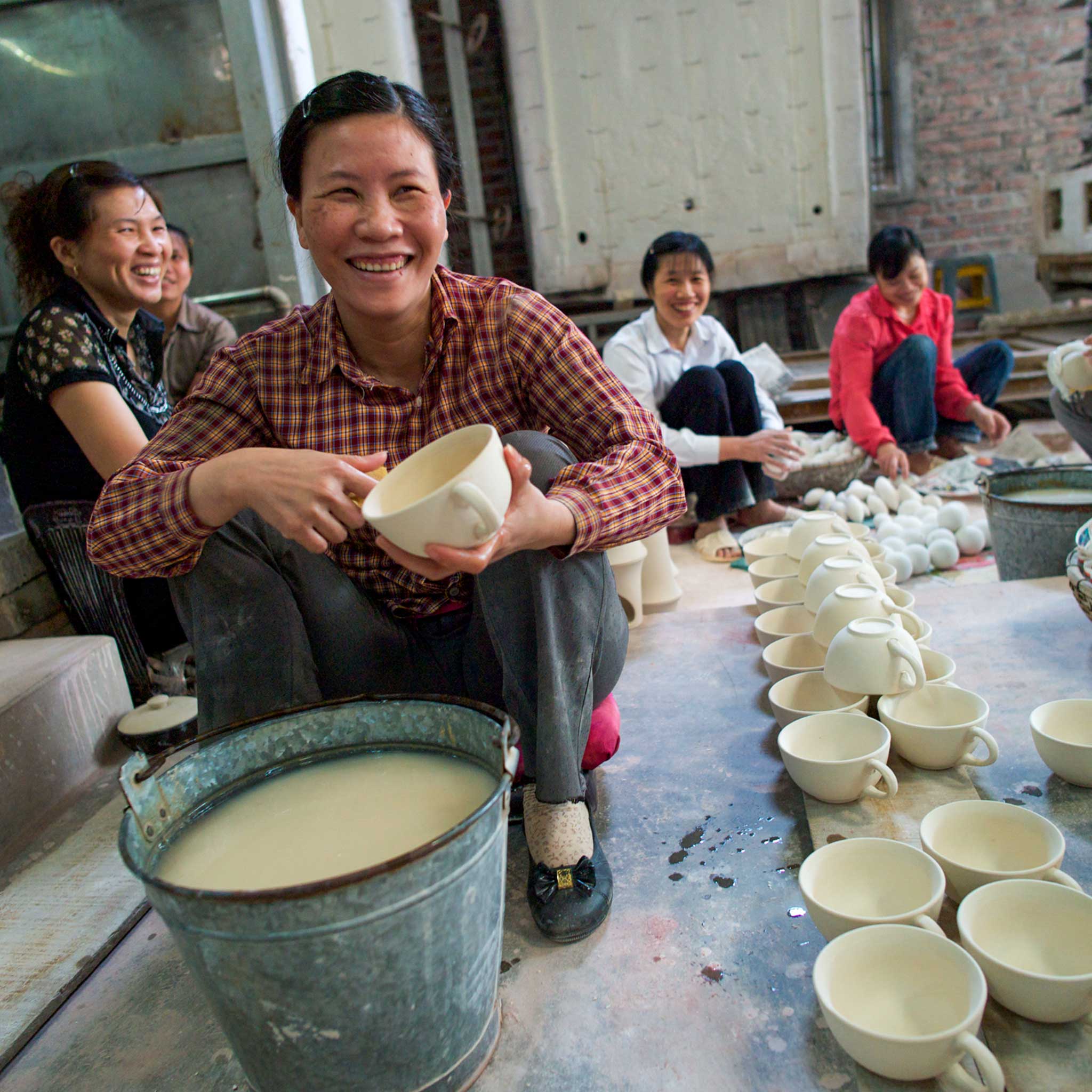 Person holding a handmade Vietnamese pottery mug filled with tea, ideal for rainy days