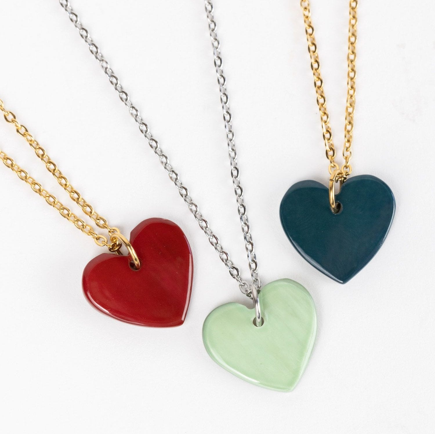 Close-up of the artisan heart necklace with red pendant on gold chain, highlighting craftsmanship