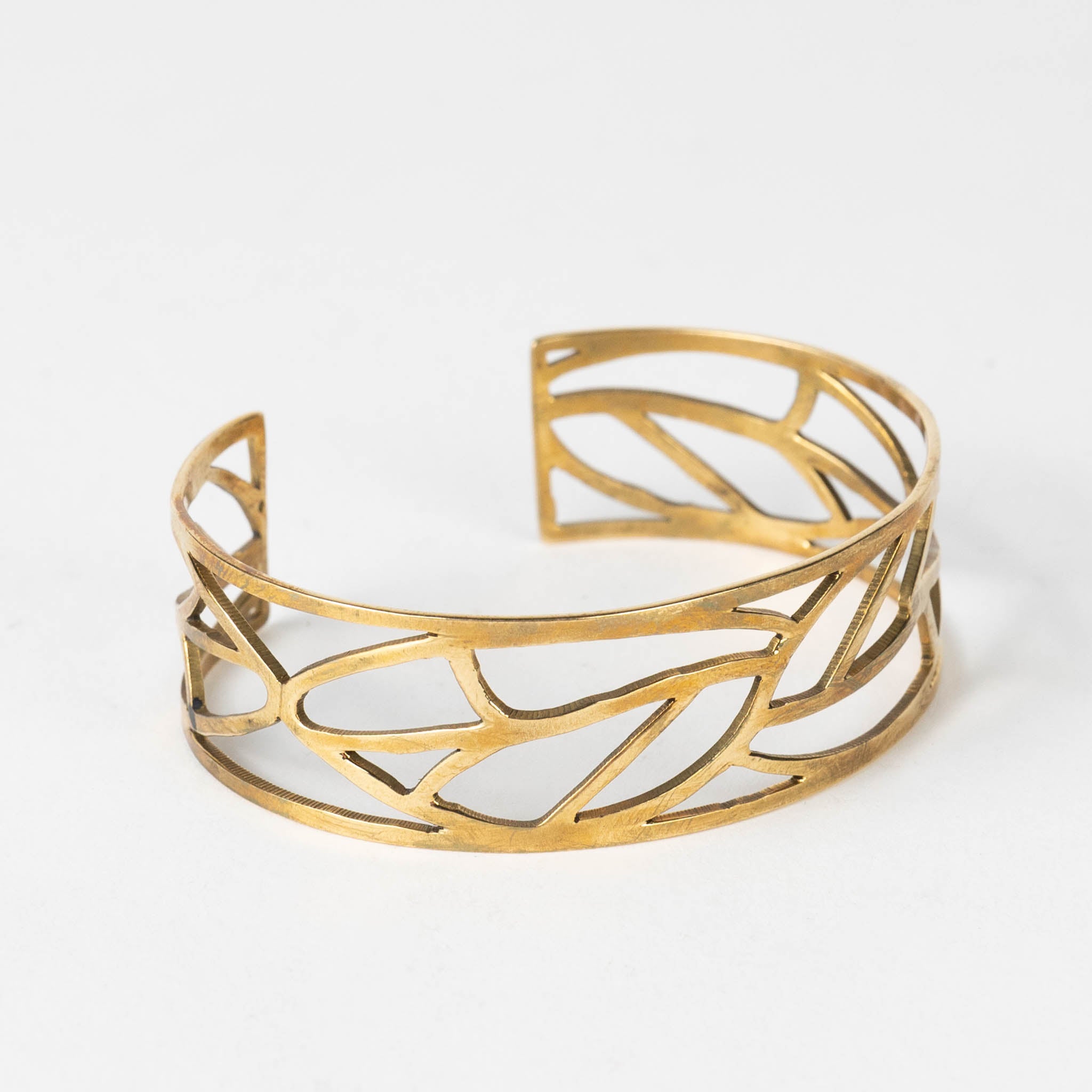 Close-up of the leaf bangle showing fine brass texture and hand-cut details.