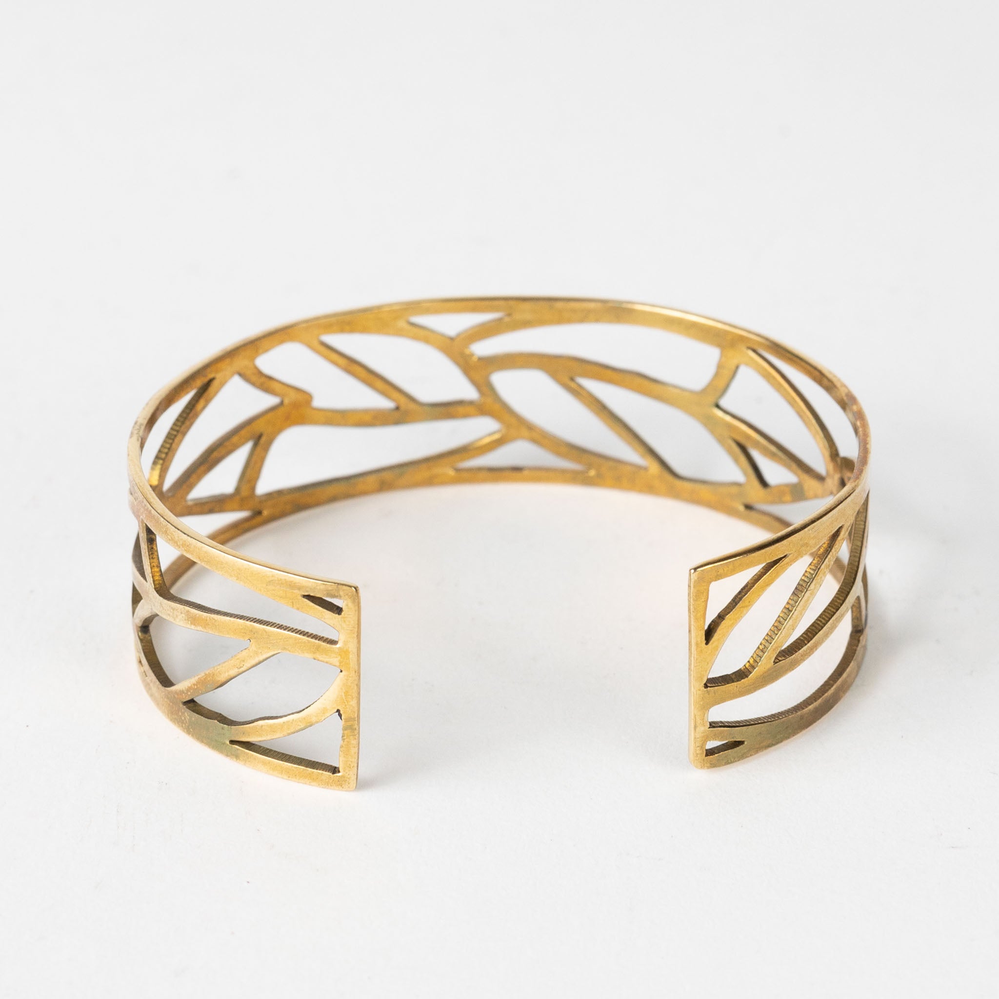 Close-up of the leaf bangle showing fine brass texture and hand-cut details.
