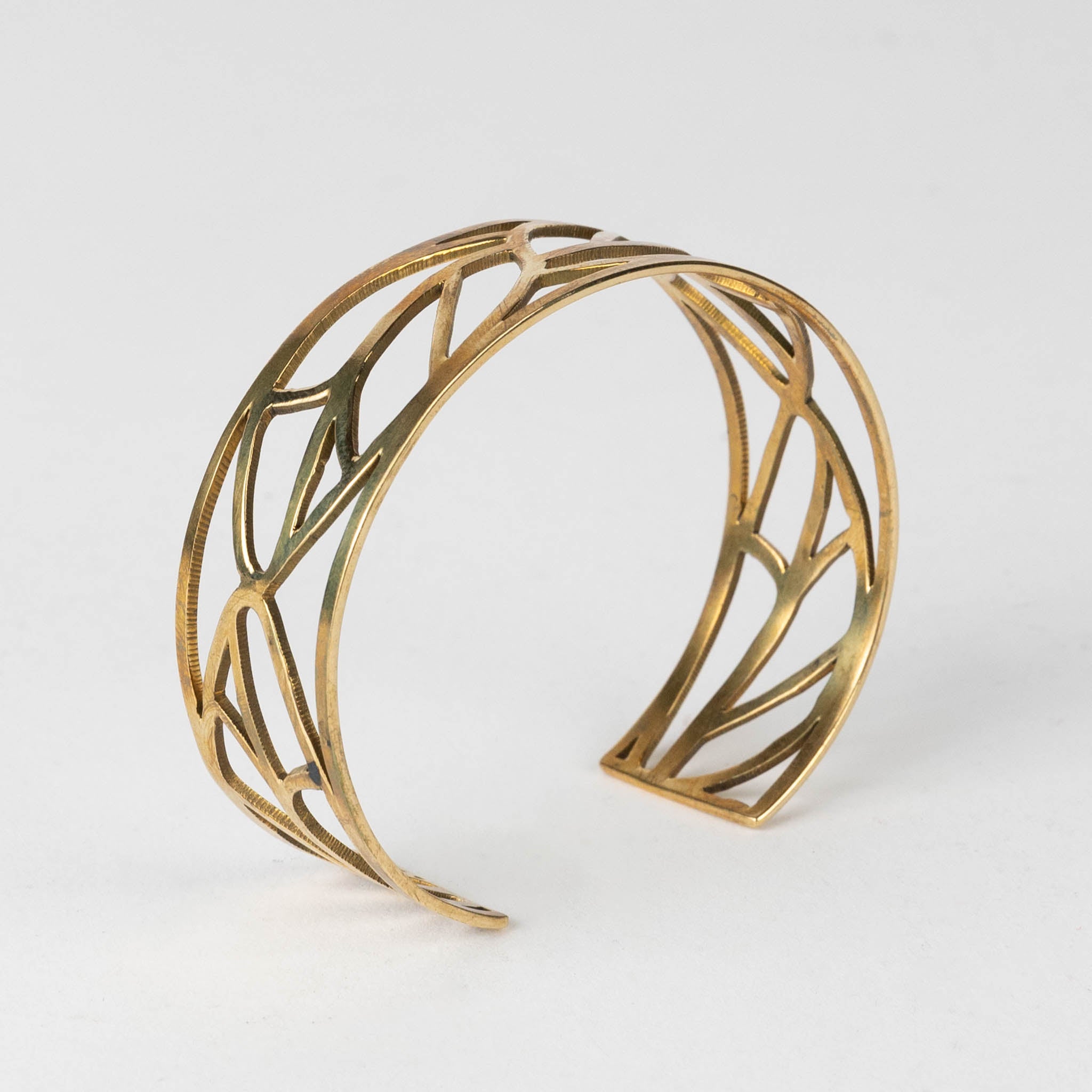 Leaf brass bangle styled with stacked hand jewelry for a layered ethnic look.
