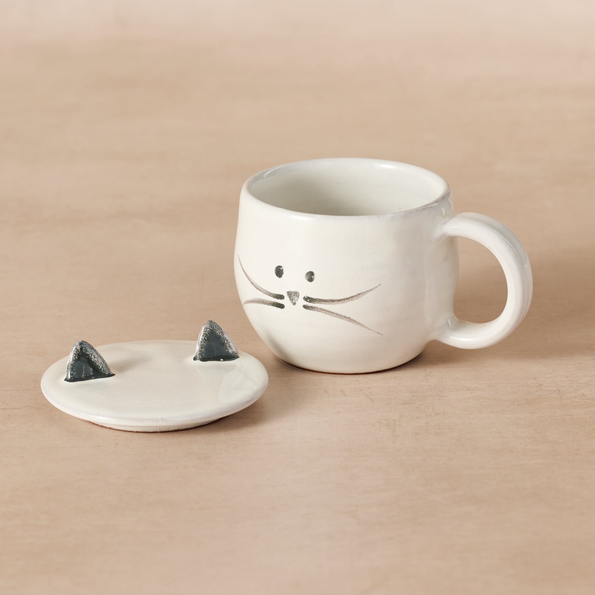 Artisan-crafted ceramic tea steeping mug displayed with tea leaves