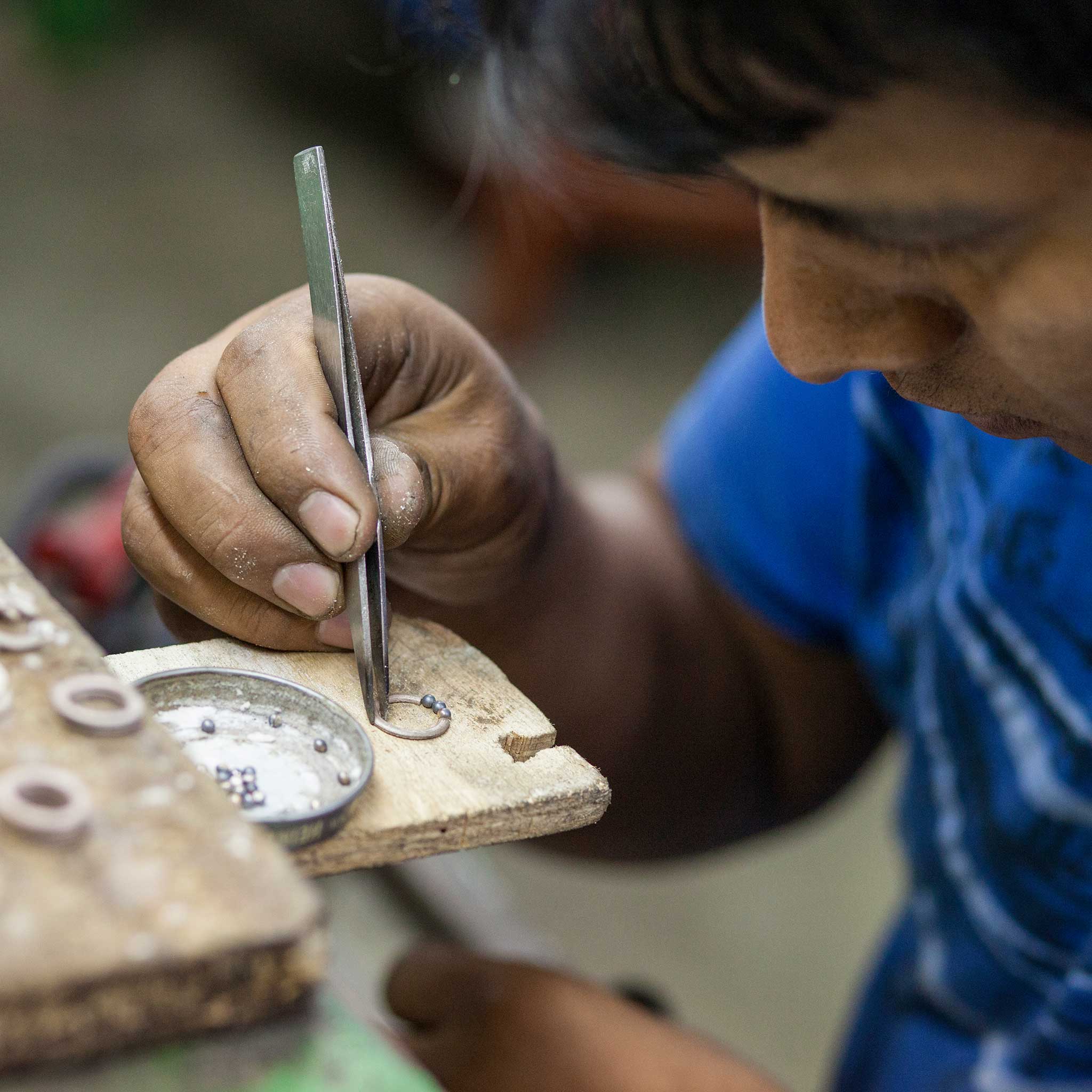 Artisan crafting silver necklaces in Peru, highlighting the detailed work on the tree pendant