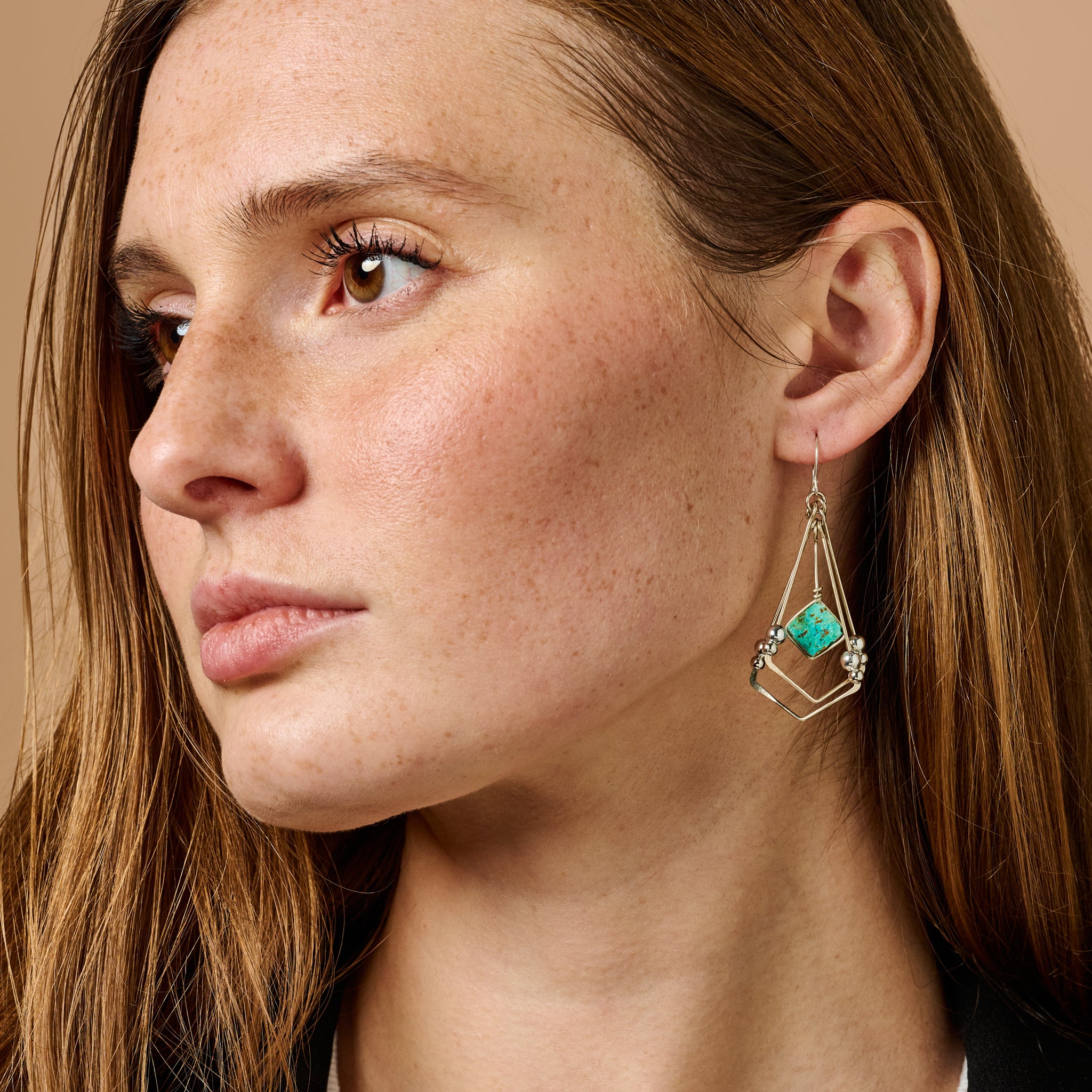 Close-up view of enchanting turquoise dangle earrings highlighting the intricate design and Peruvian turquoise.