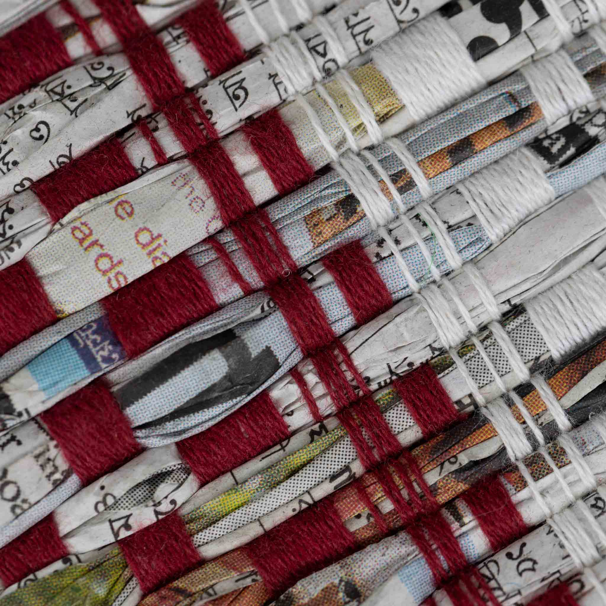 Artisan weaving recycled newspapers into durable woven placemats for eco-friendly dining