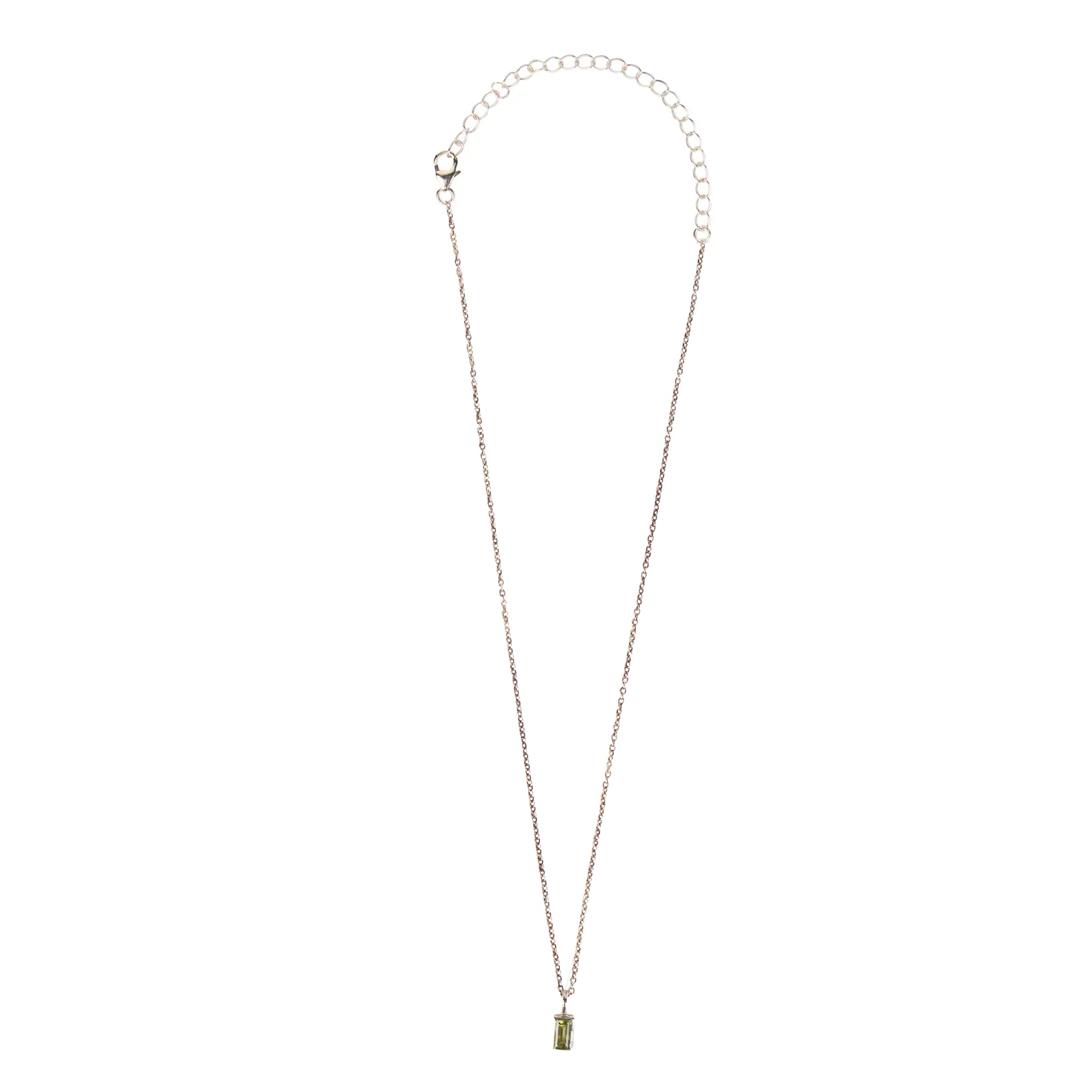 Close-up of artisan peridot silver pendant necklace highlighting its baguette cut.