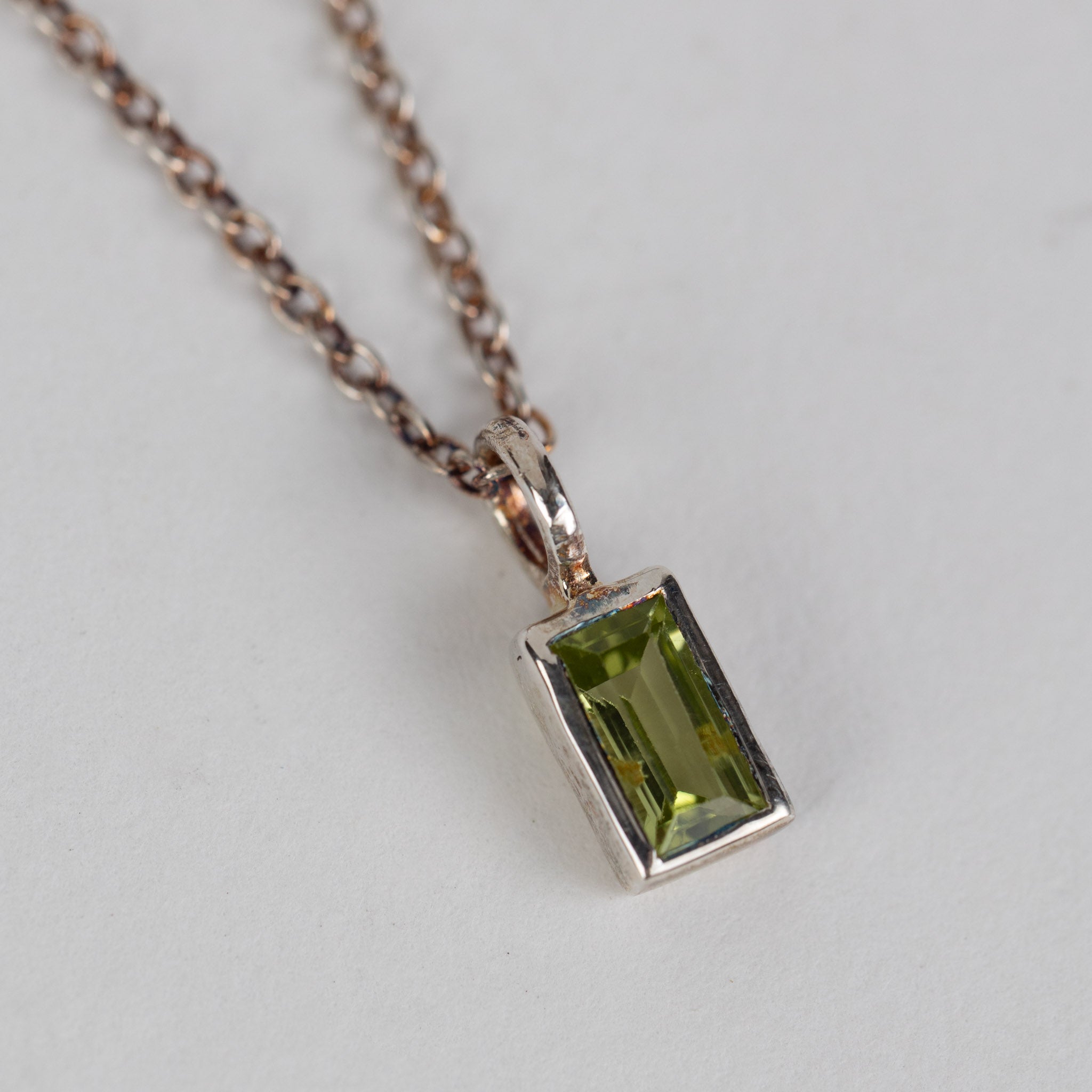 Close-up of artisan peridot silver pendant necklace highlighting its baguette cut.