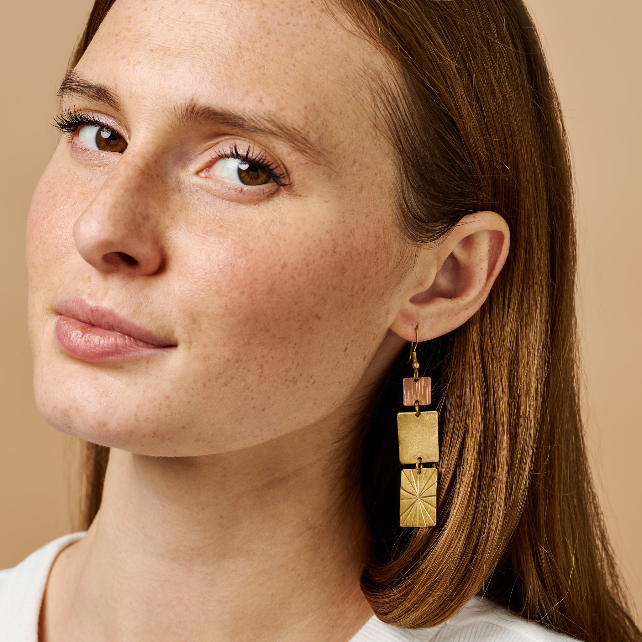 Close-up view of the Sunburst Elegance Dangle Earrings showcasing the intricate design and copper-brass finish.