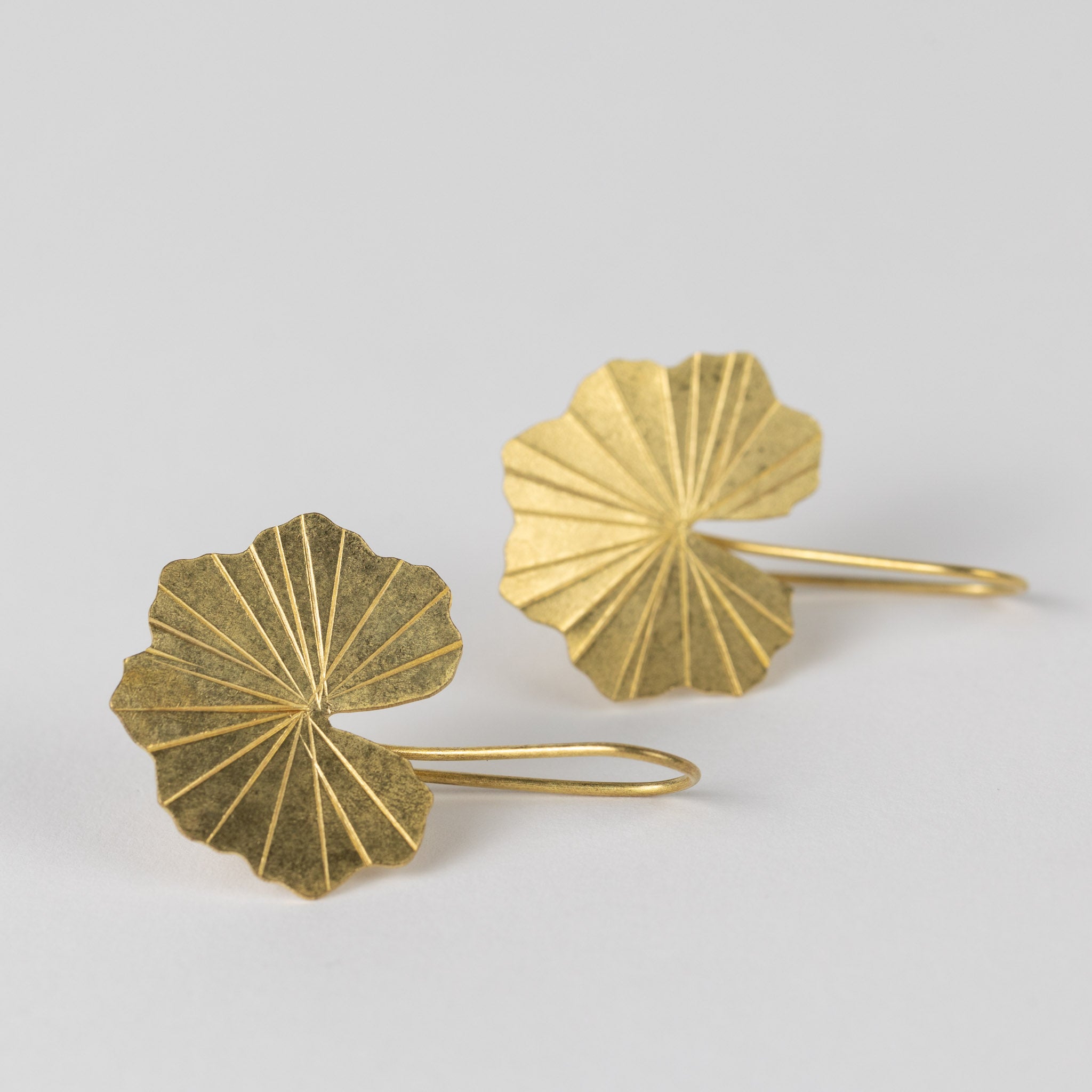 Stylish woman wearing handcrafted brass drop earrings with a casual outfit.