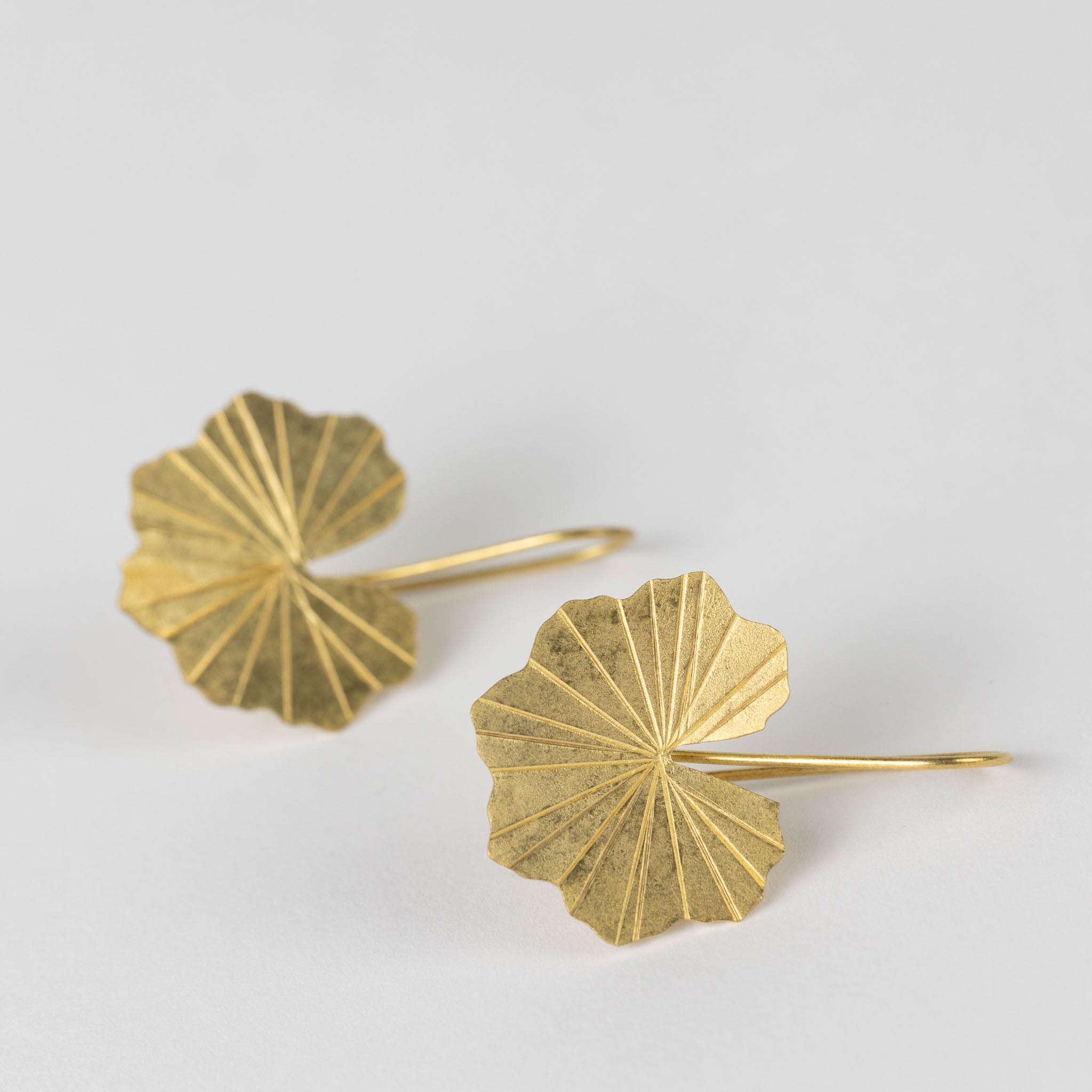 Elegant display of artisan brass drop earrings on a decorative background.