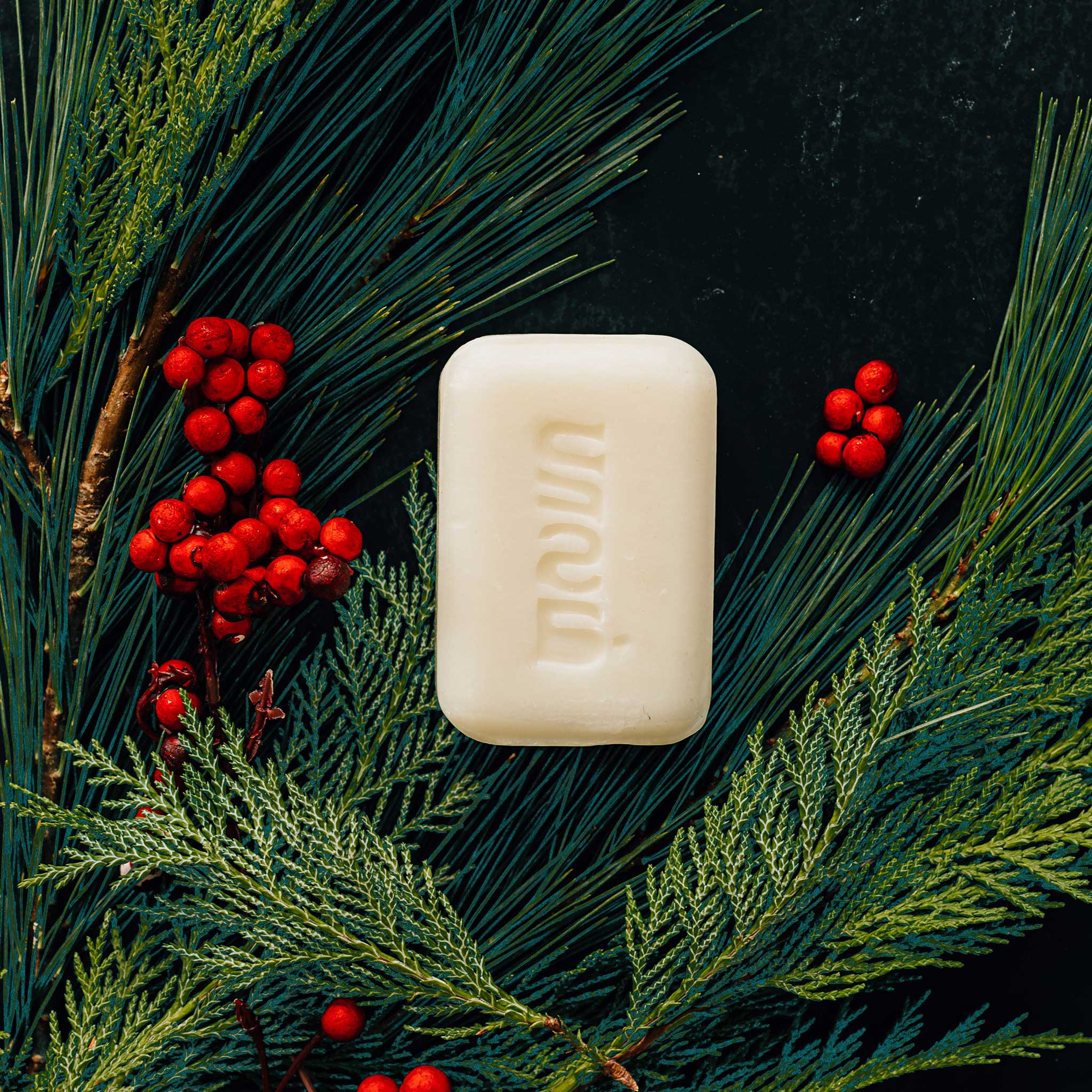 Handcrafted mistletoe soap displayed with holiday decorations, showcasing its rich textures.