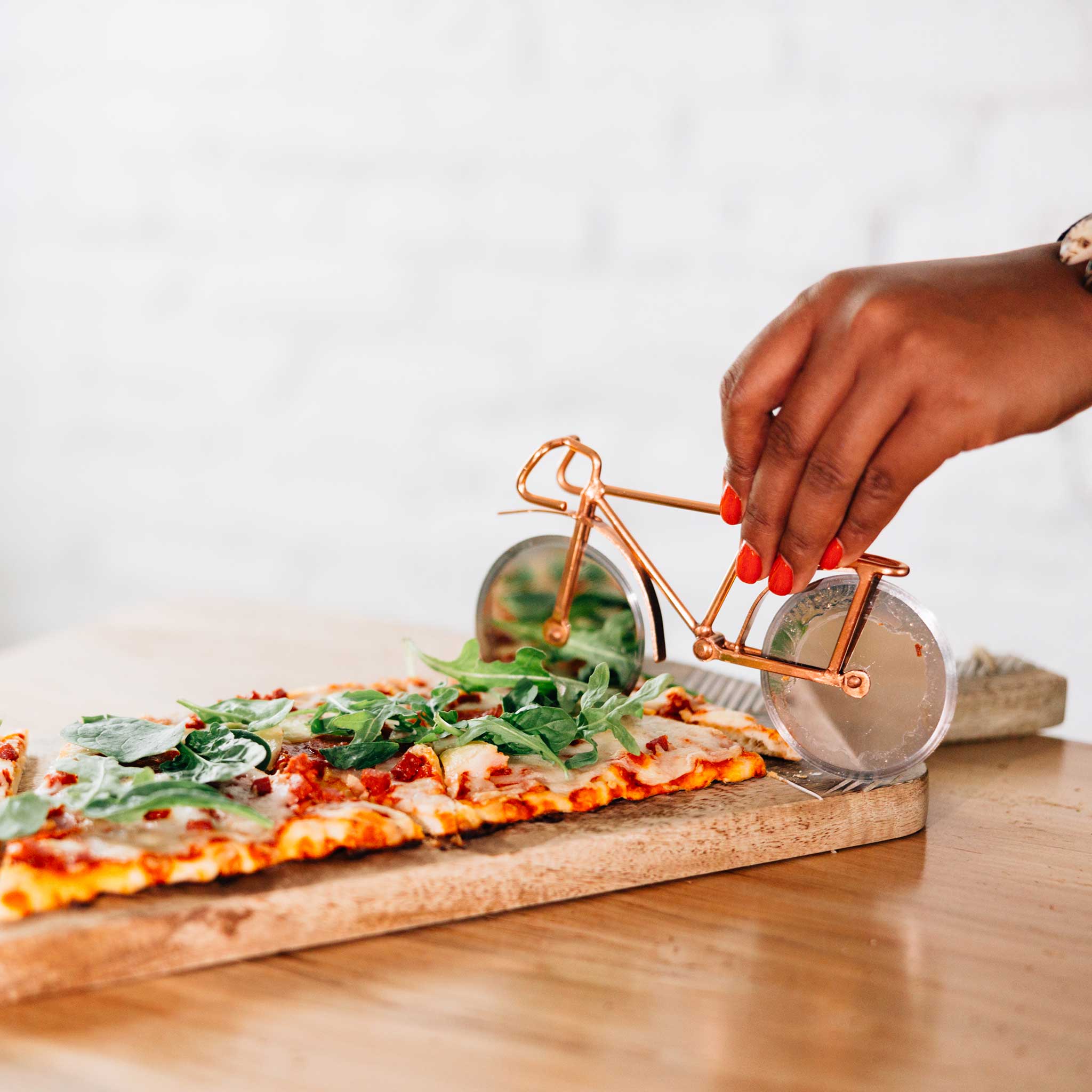 Stainless steel pizza cutter in use, effortlessly slicing a delicious pizza.