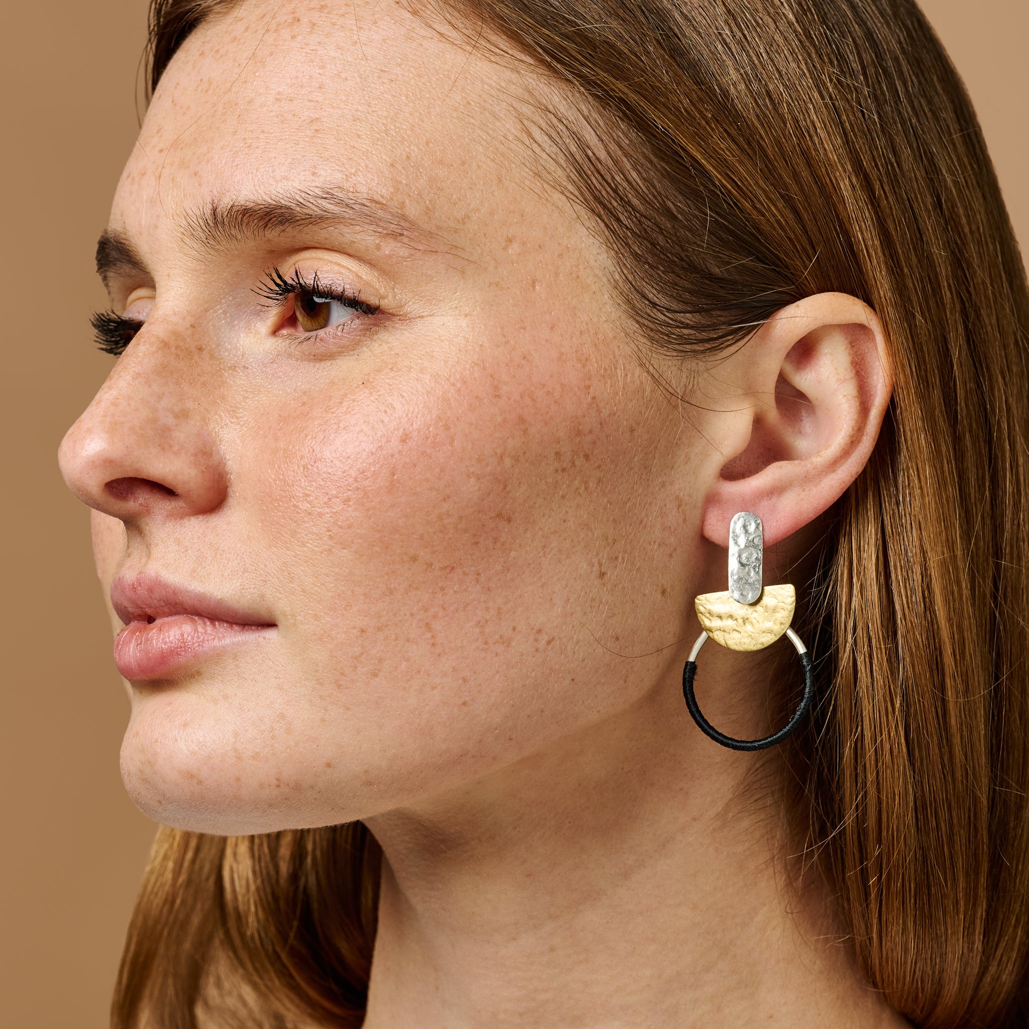 Close-up of modern silver hoop earrings with black thread accents for everyday style