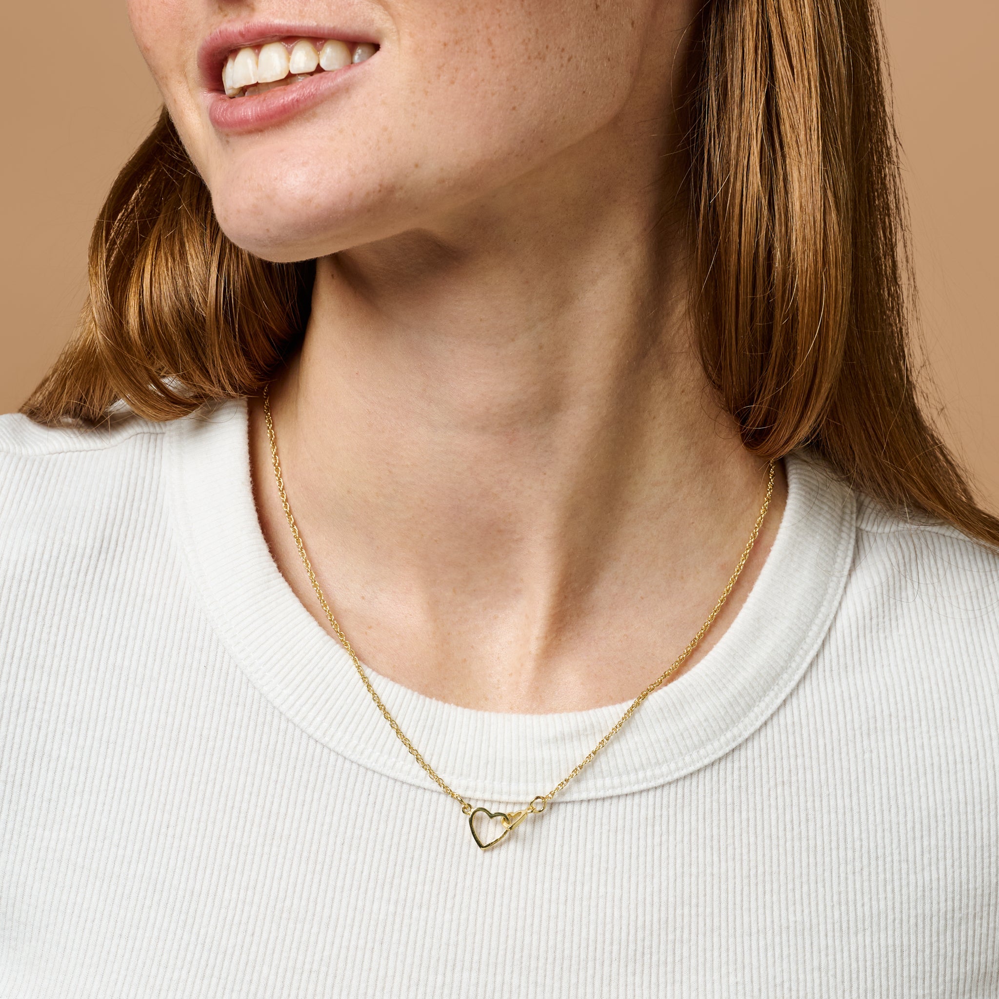 Close-up of brass necklace with two linked hearts resting on linen, showcasing handmade detailing