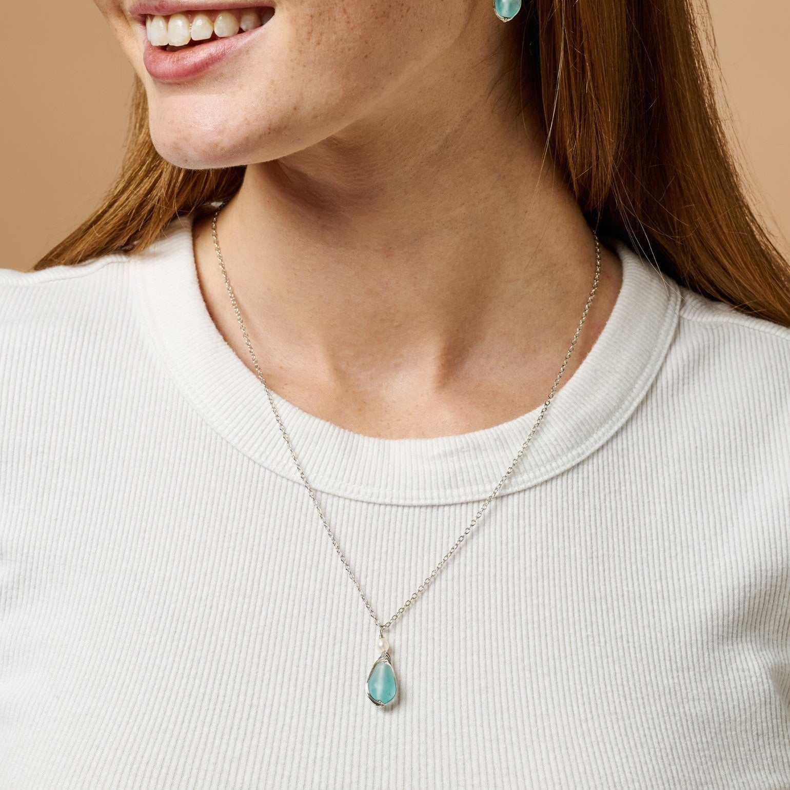 Close-up of frosted aqua glass bead on handcrafted silver pendant necklace