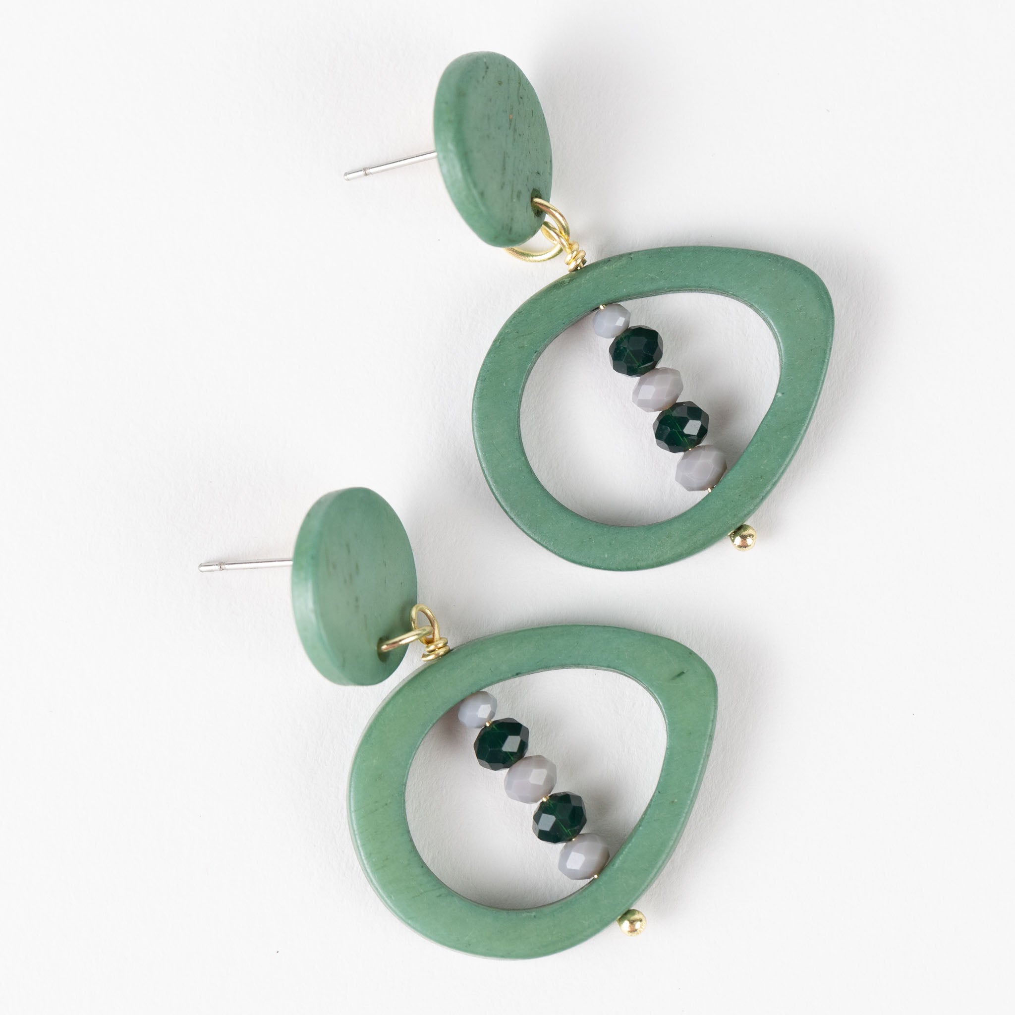 Close-up of handcarved green eyes on bone earrings with glass beads, artisan jewelry for women