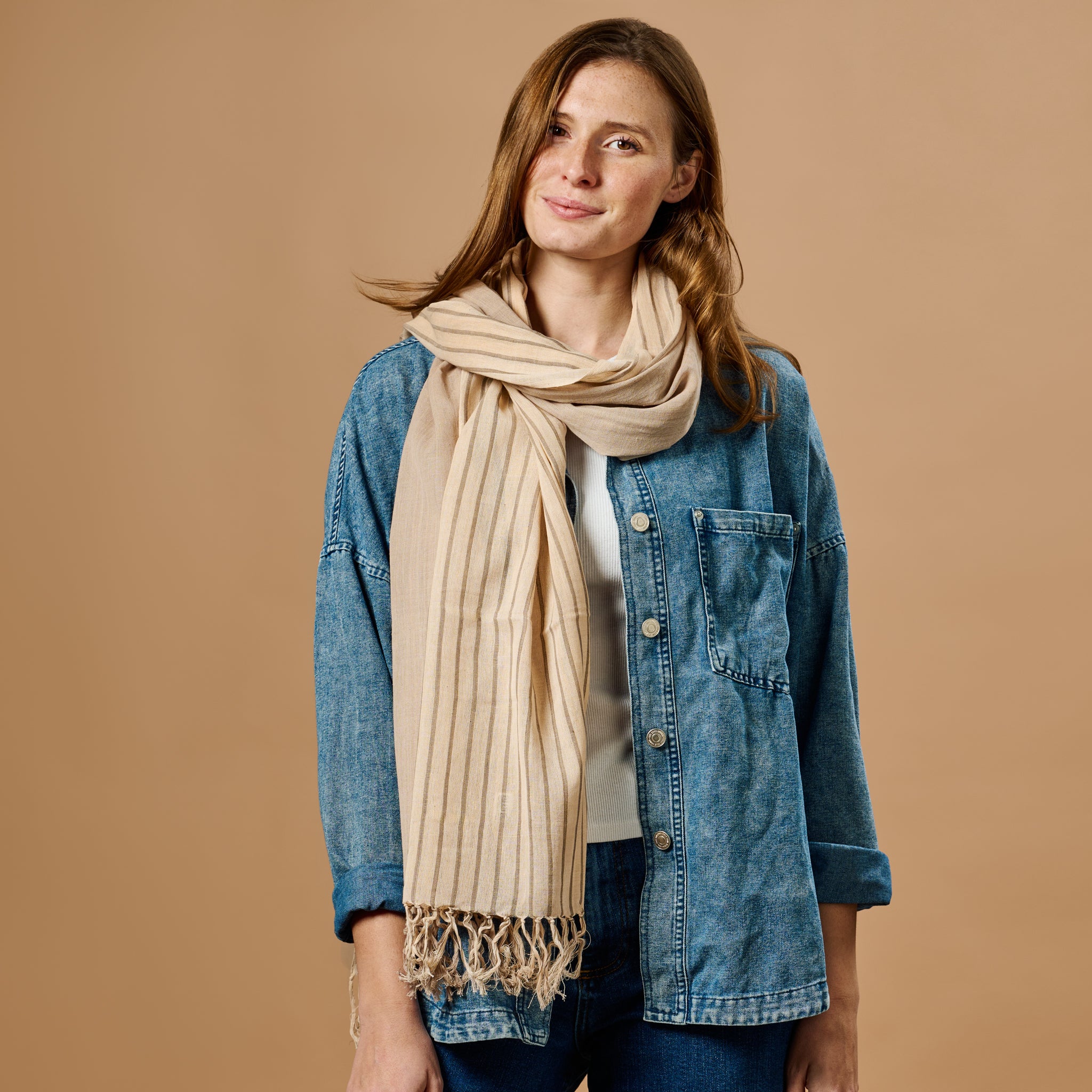 Cinnamon striped cotton scarf draped elegantly over a chair, showcasing its vibrant colors and texture.
