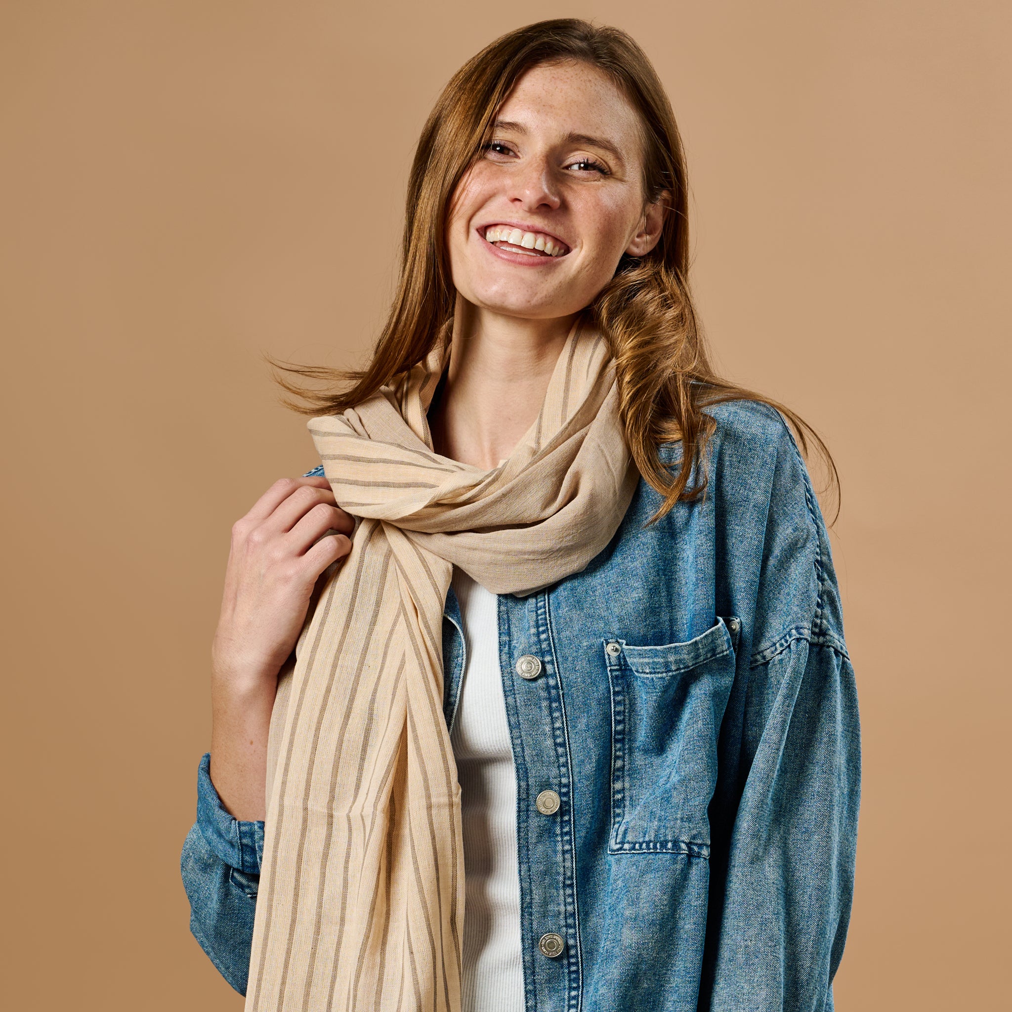 A woman wearing the cinnamon striped scarf while enjoying a walk in the park, demonstrating its stylish appeal.