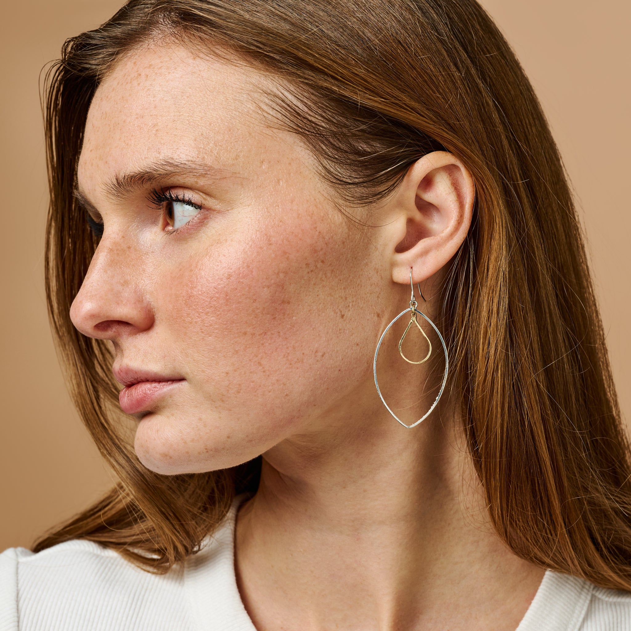 Close-up of delicate petal earrings showing gold and silver tones