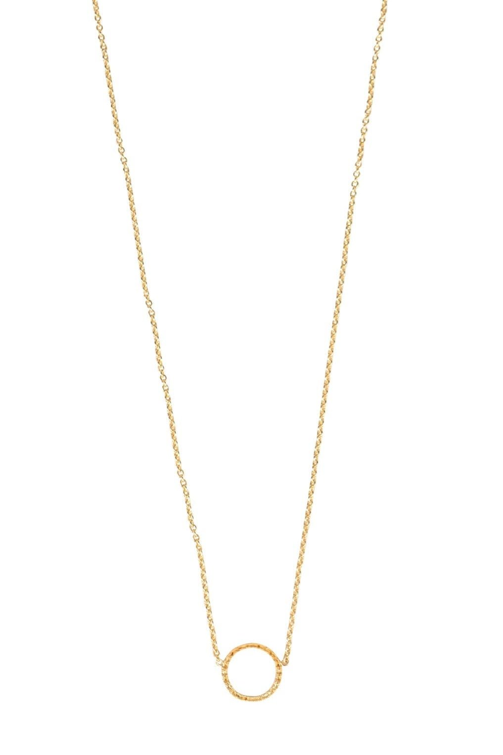 Close-up of minimalist circle pendant necklace on a model's neckline showcasing handcrafted design