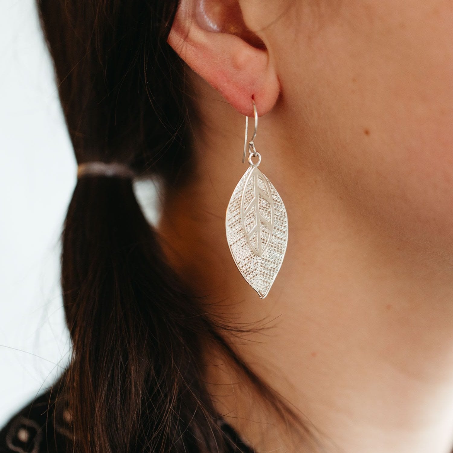 Close-up of artisan silver leaf earrings highlighting the filigree detail.