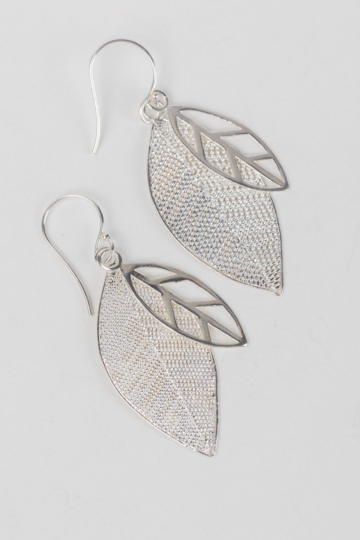 Model wearing handcrafted silver leaf earrings in a casual setting.