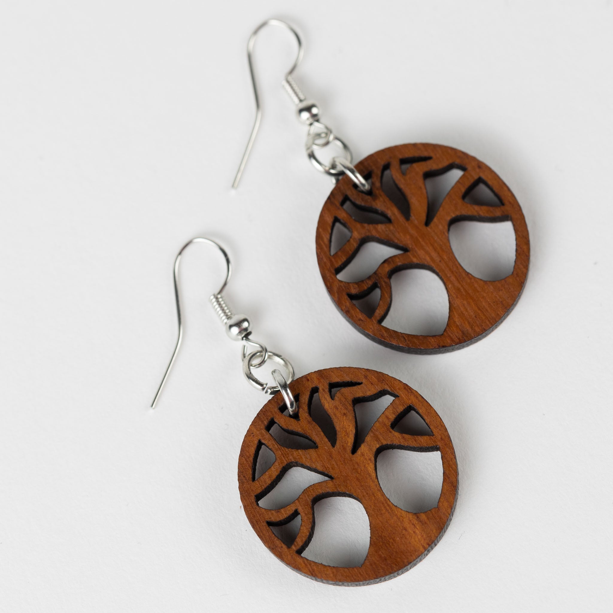 Close-up of handcrafted Tree of Life wooden dangle earrings showcasing natural wood grain.