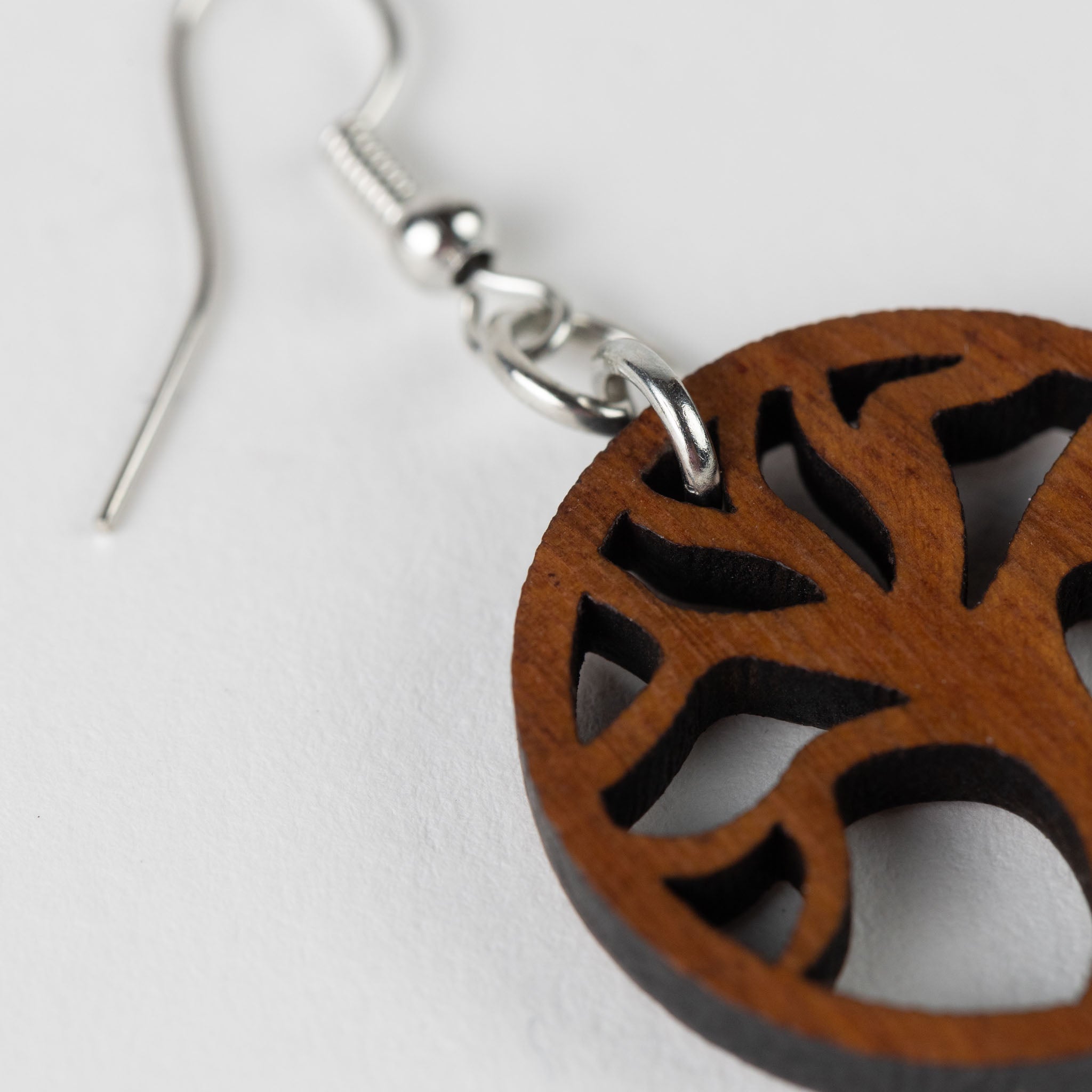 Artistic shot of Tree of Life earrings on a wooden surface, emphasizing their unique craftsmanship.