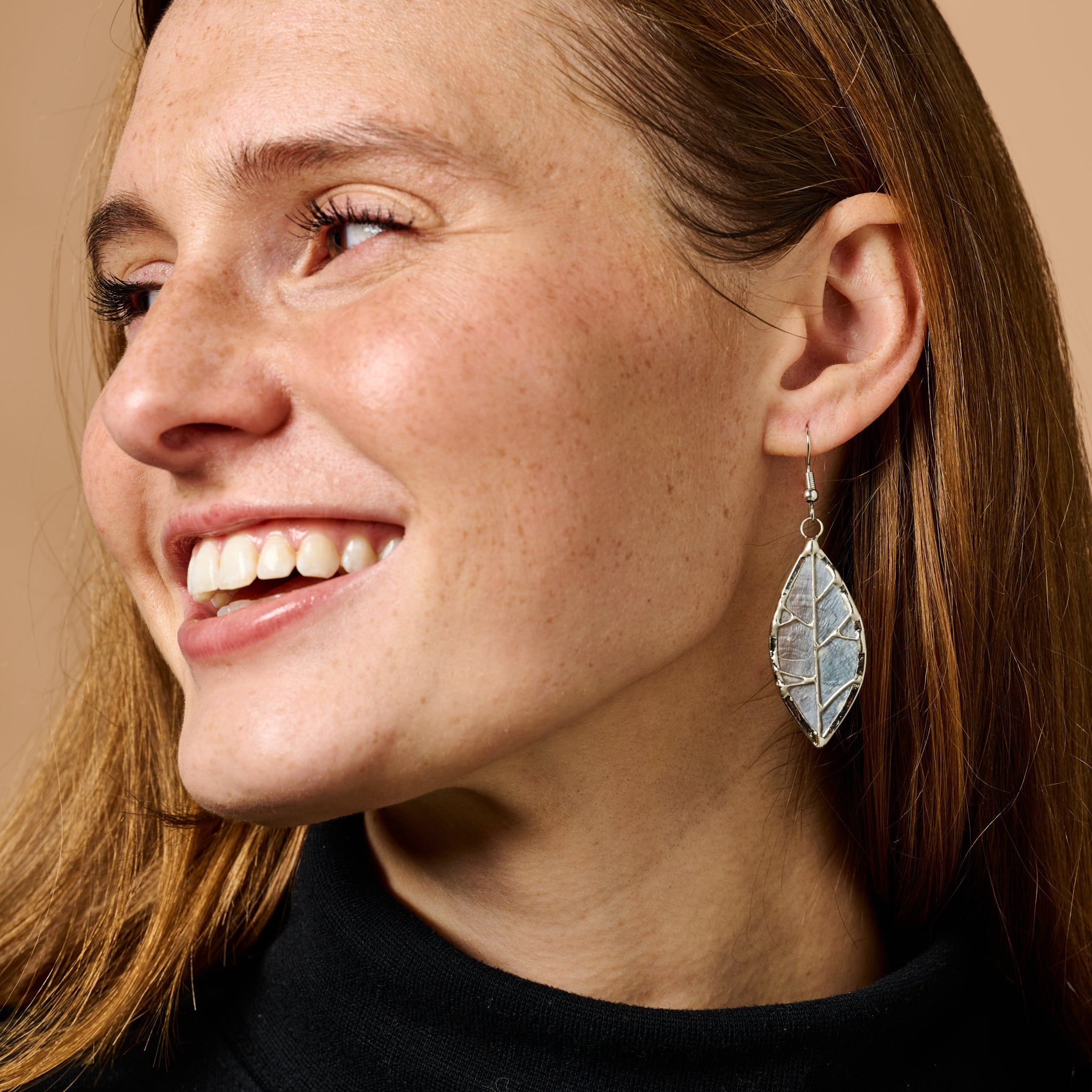 Side view of handmade leaf capiz earrings highlighting the shell material and craftsmanship