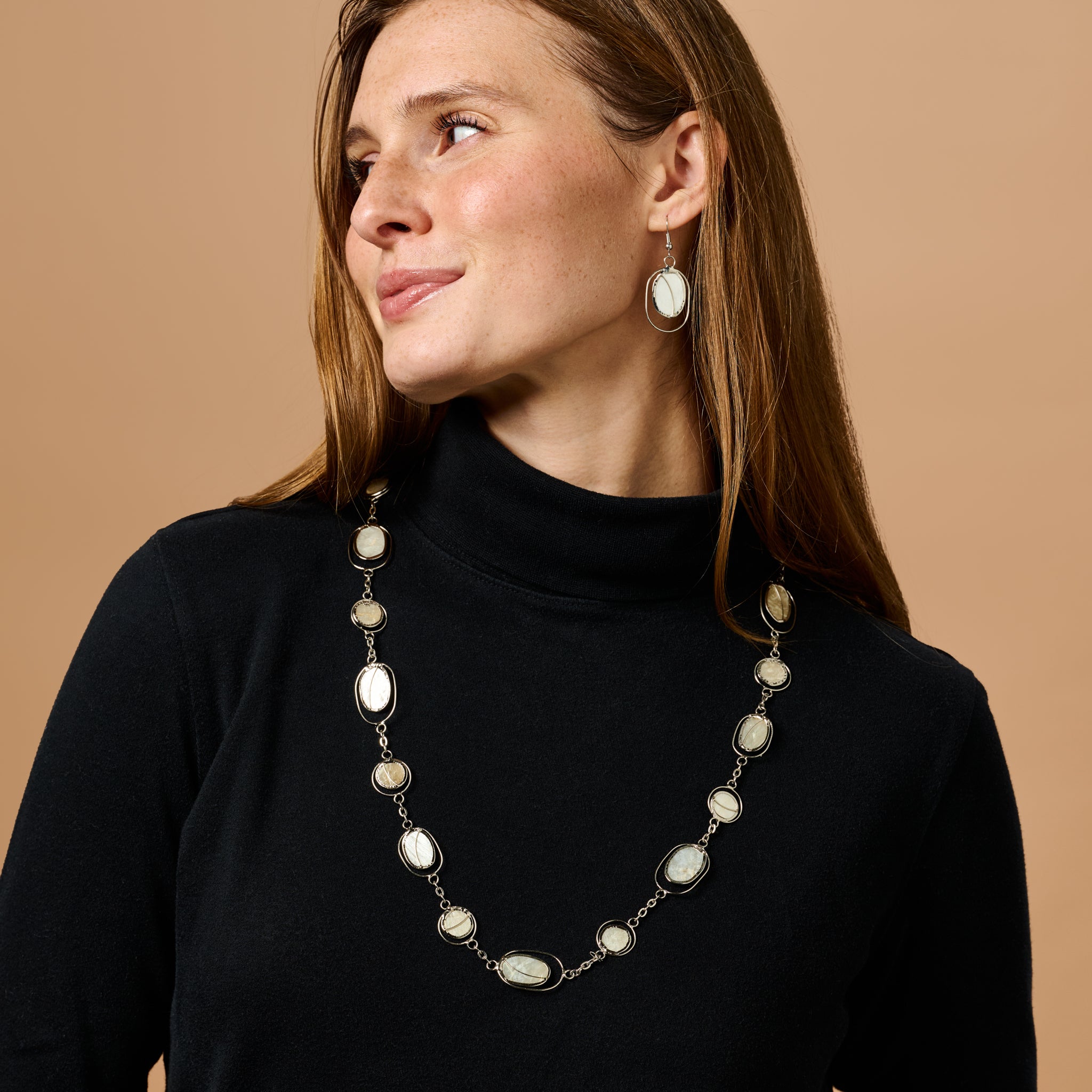 Elegant capiz shell earrings displayed on a wooden surface, highlighting their unique design.