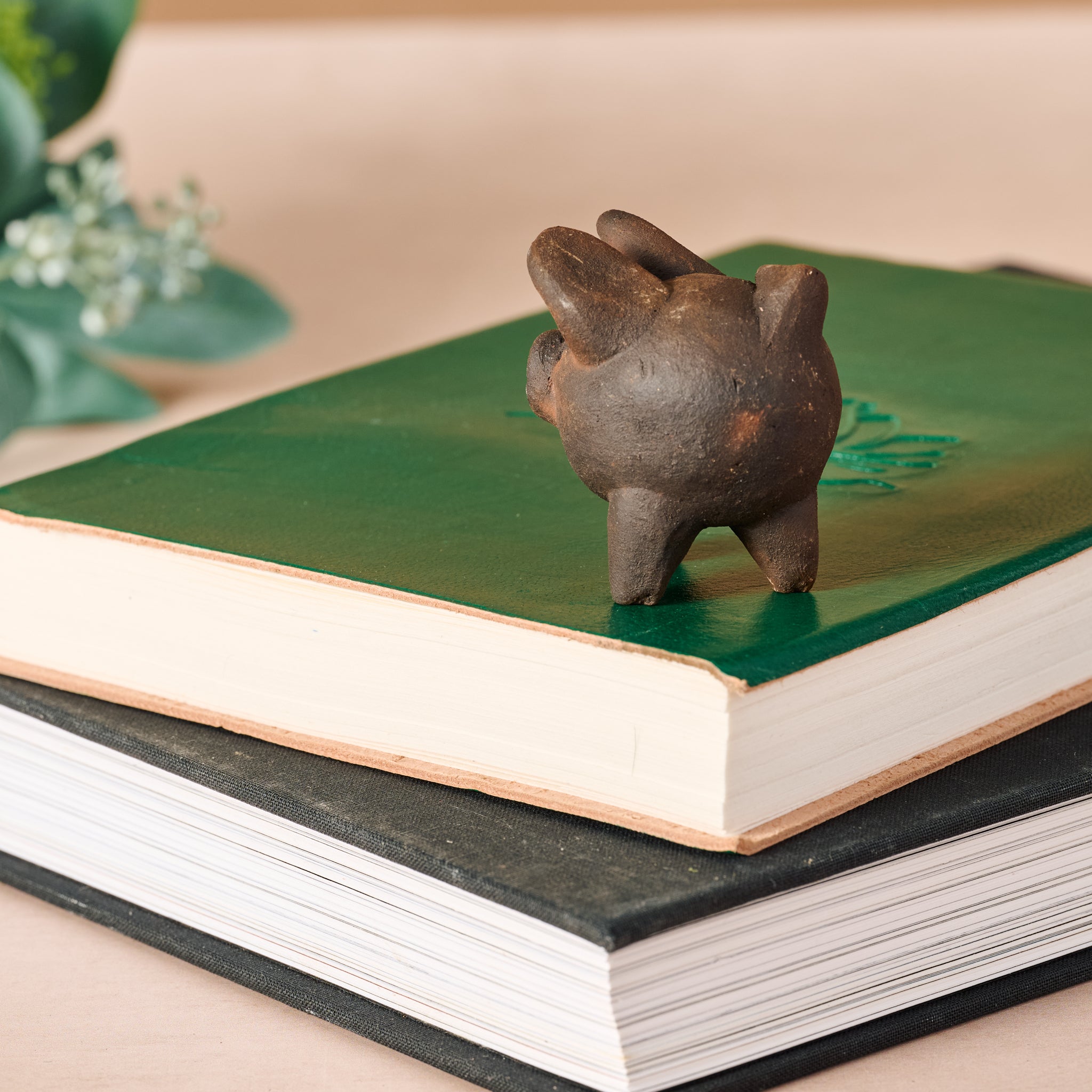 Small terracotta pig for luck displayed on a decorative shelf.