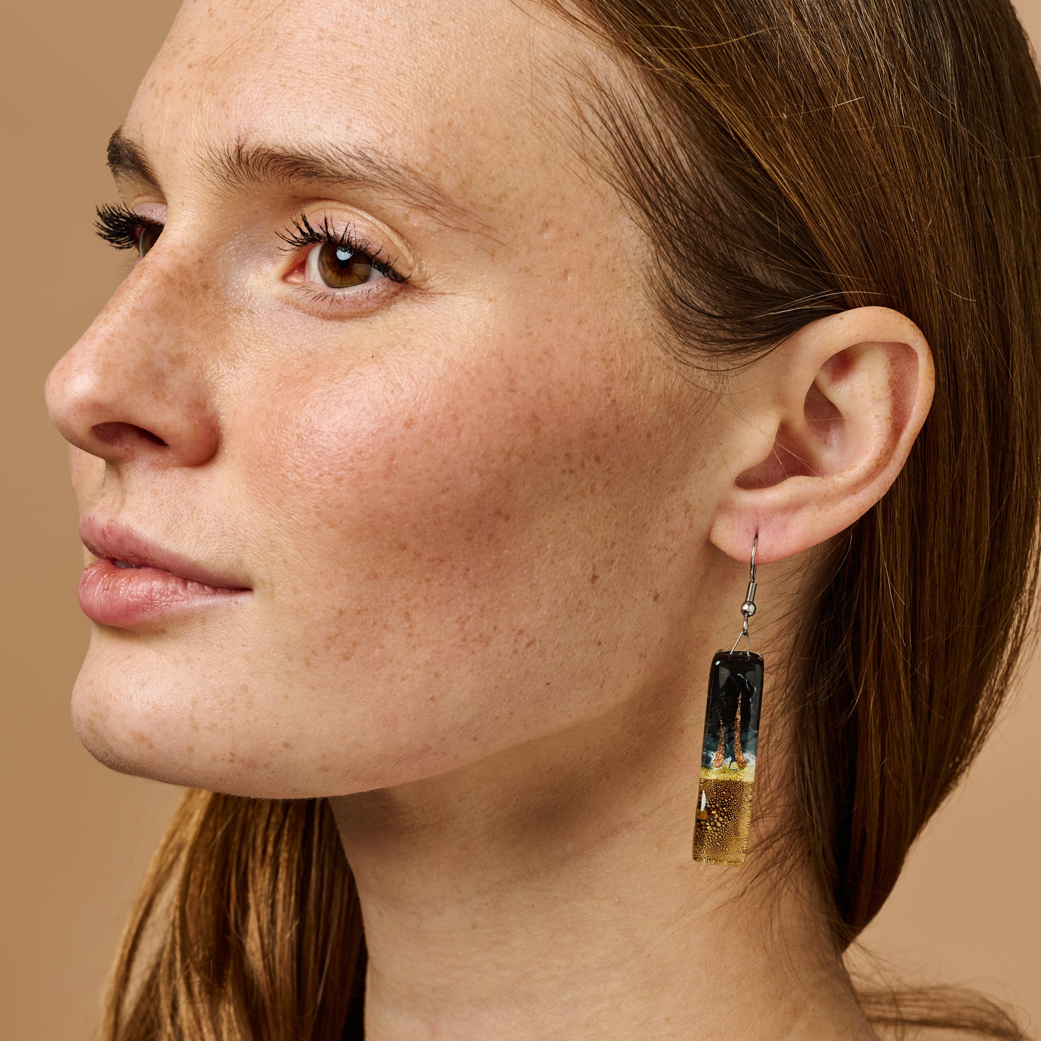 Close-up of LunaGlow artisan earrings showing iridescent glass swirls