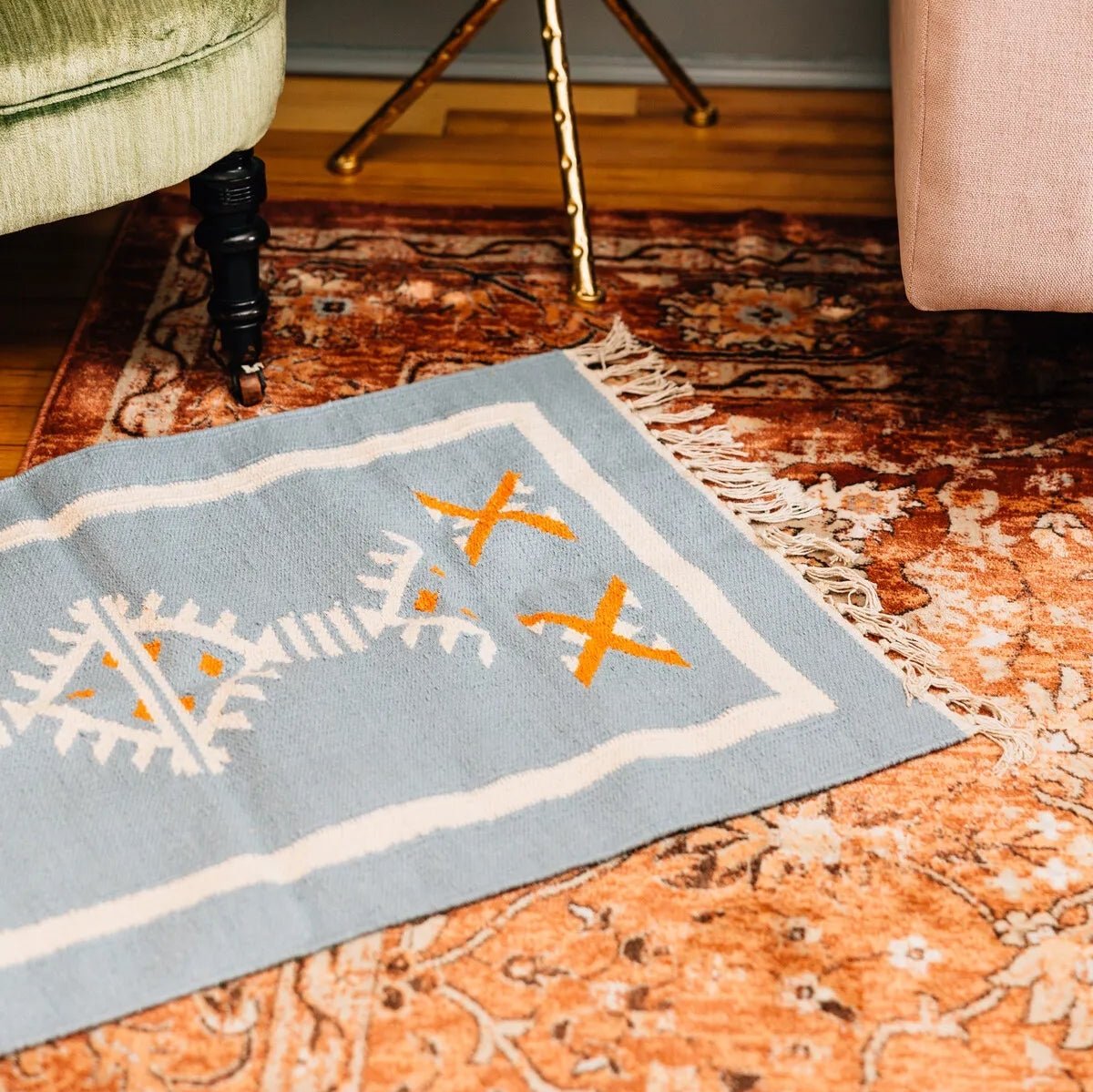 Close-up of the vibrant orange, cream, and blue woven details on the dhurrie rug