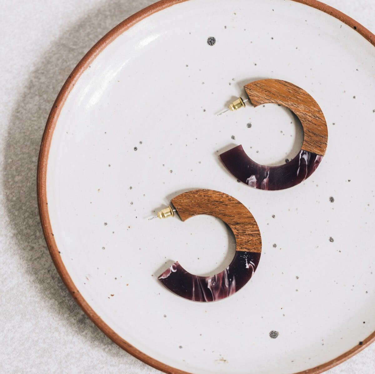 Close-up of eco-friendly teak wood hoop earrings showcasing resin details.