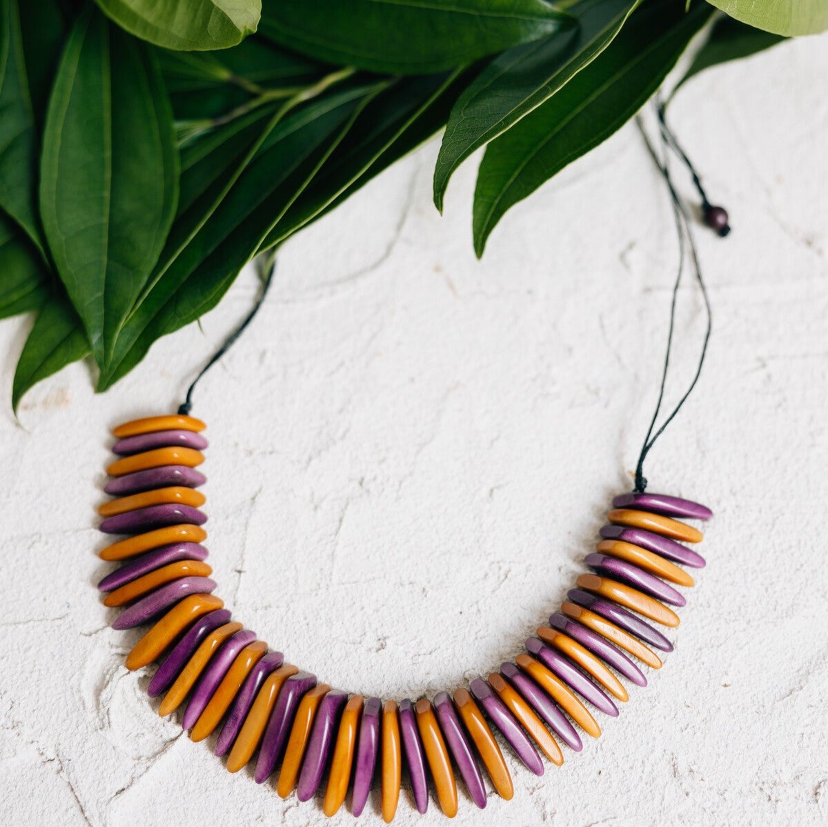 Model wearing the handmade Tagua bib necklace with a white tee, showcasing its bold statement look