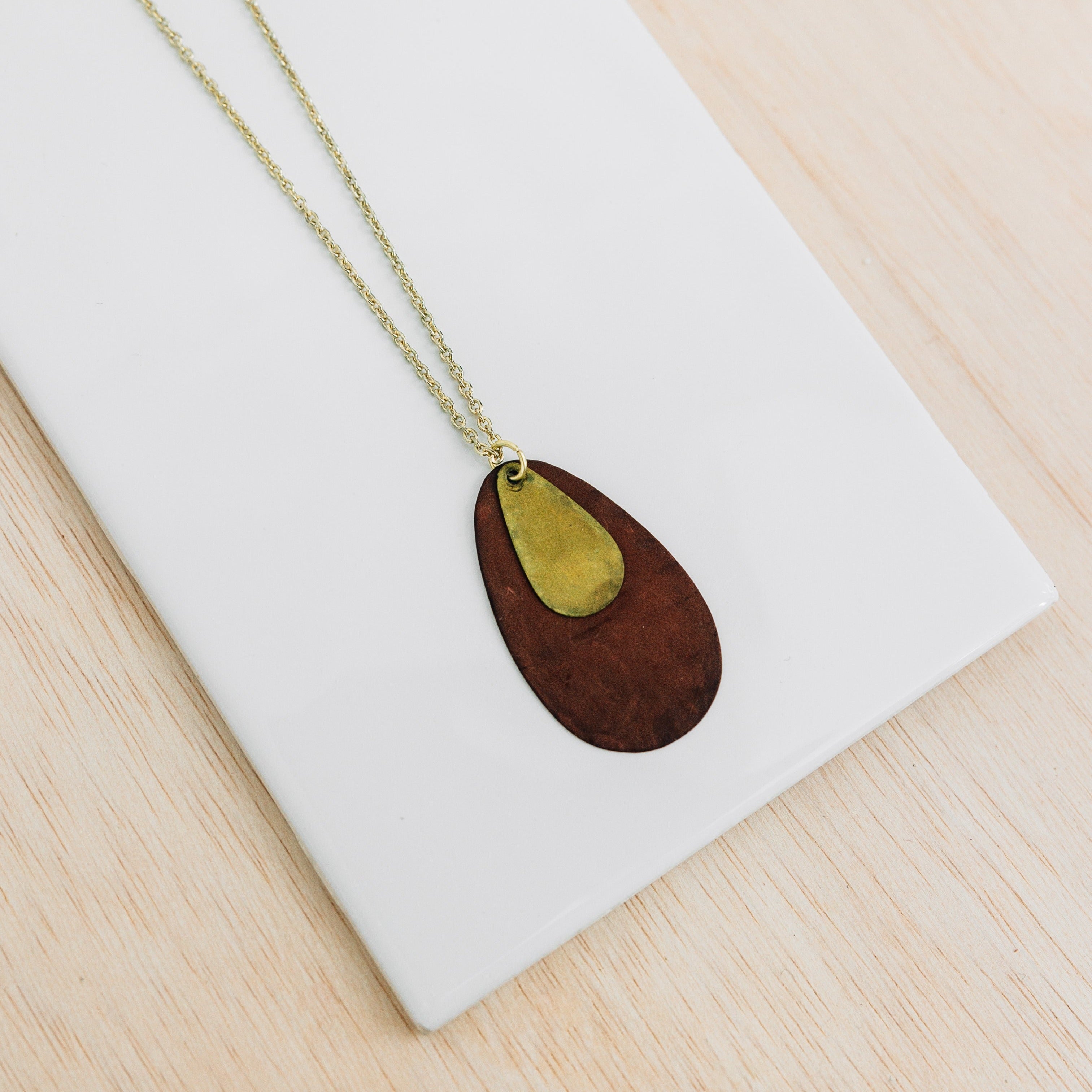 Golden Petal Artisan Layered Necklace draped elegantly on a wooden background, highlighting its intricate design.