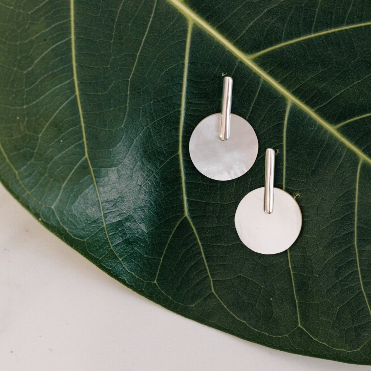 Close-up of handcrafted mother-of-pearl sterling silver earrings showcasing intricate details
