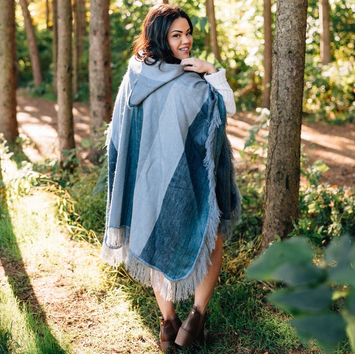 A woman wearing the hooded poncho while walking through a snowy landscape, demonstrating its warmth.