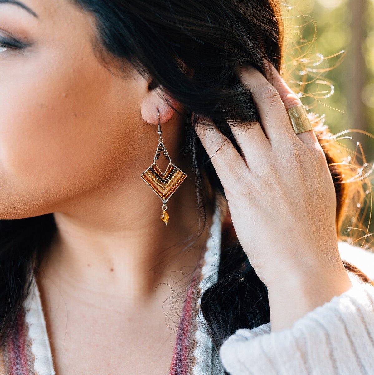 Front view of handmade beaded earrings with gold accents shown against a neutral backdrop