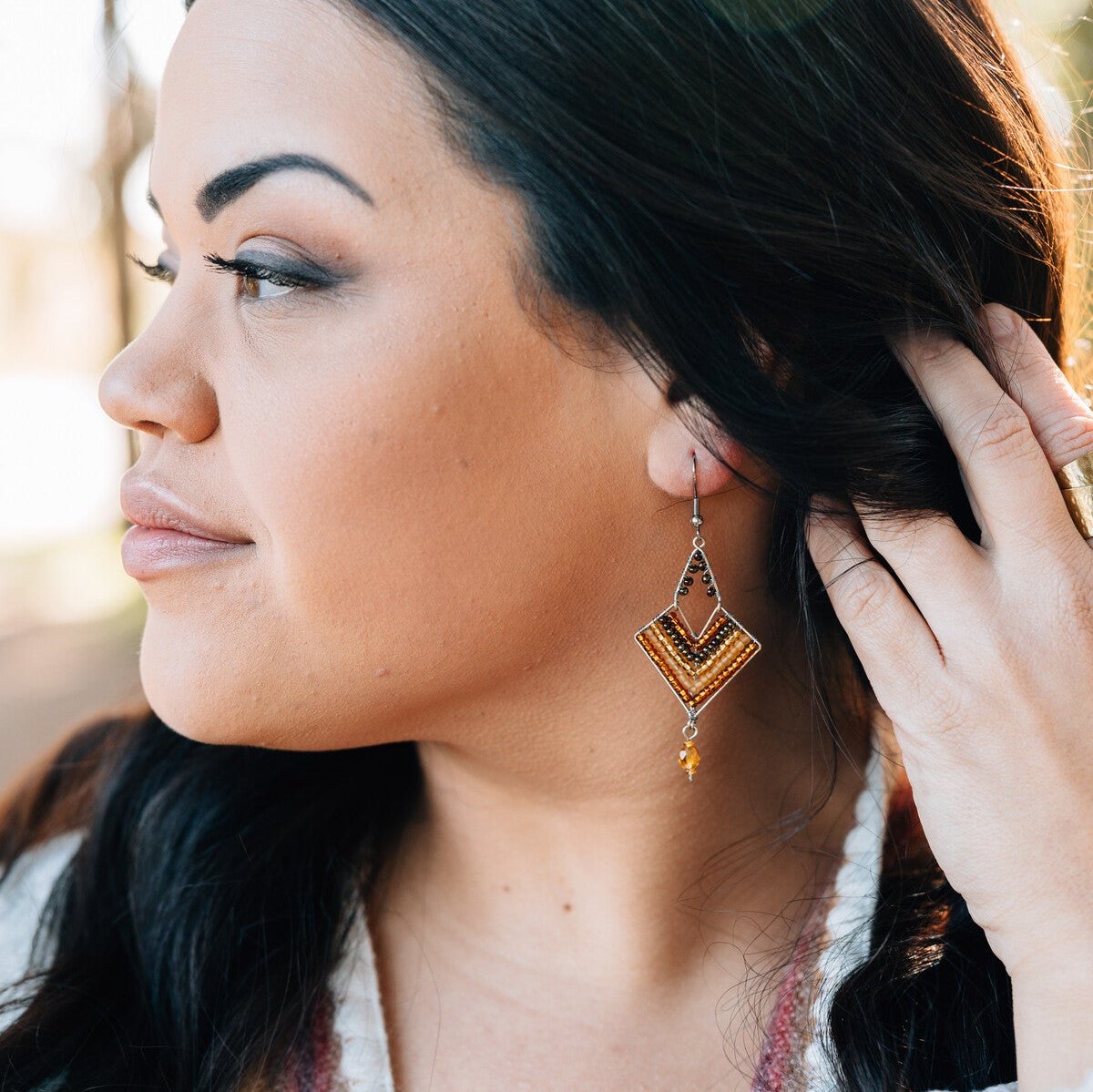 Front view of handmade beaded earrings with gold accents shown against a neutral backdrop