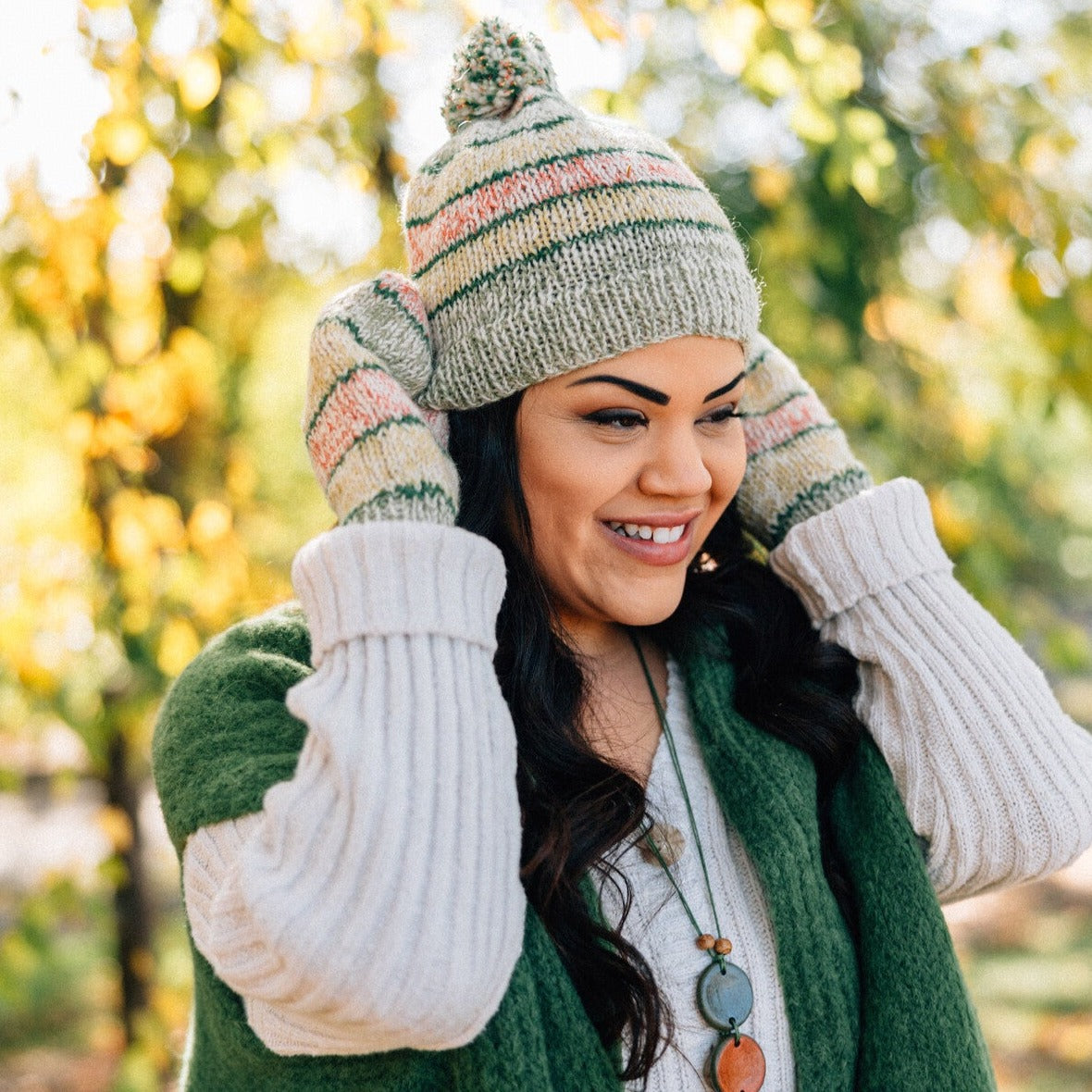 Handcrafted Artisan Candy Shoppe Mittens folded neatly next to a winter hat, ready for use.