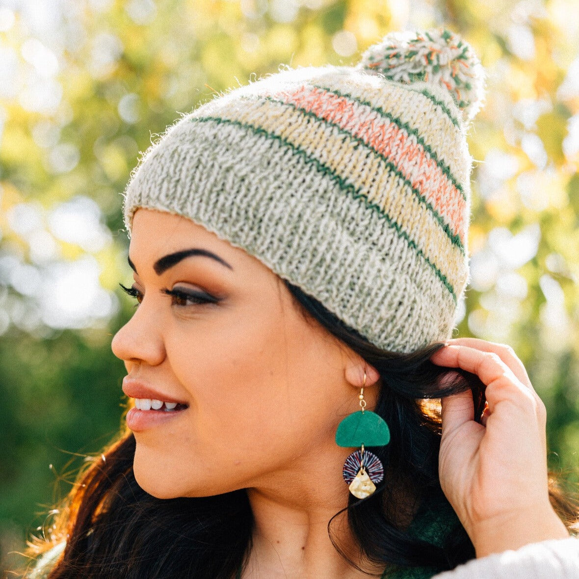 Front view of a handmade wool beanie with pom pom on a model outdoors